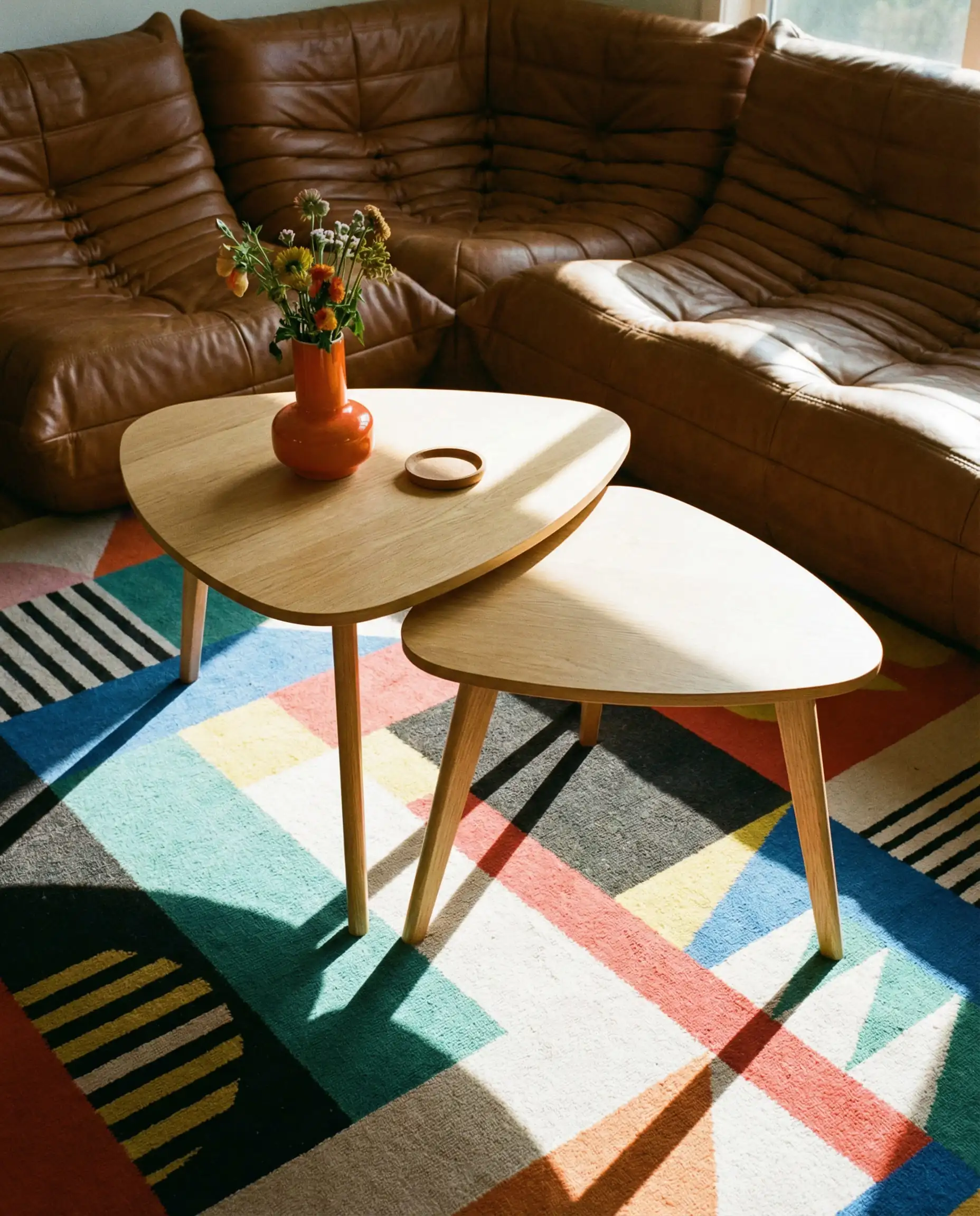 Top view of triangular guitar-pick shaped oak nesting tables breaking up the square lines of a brown leather sectional.