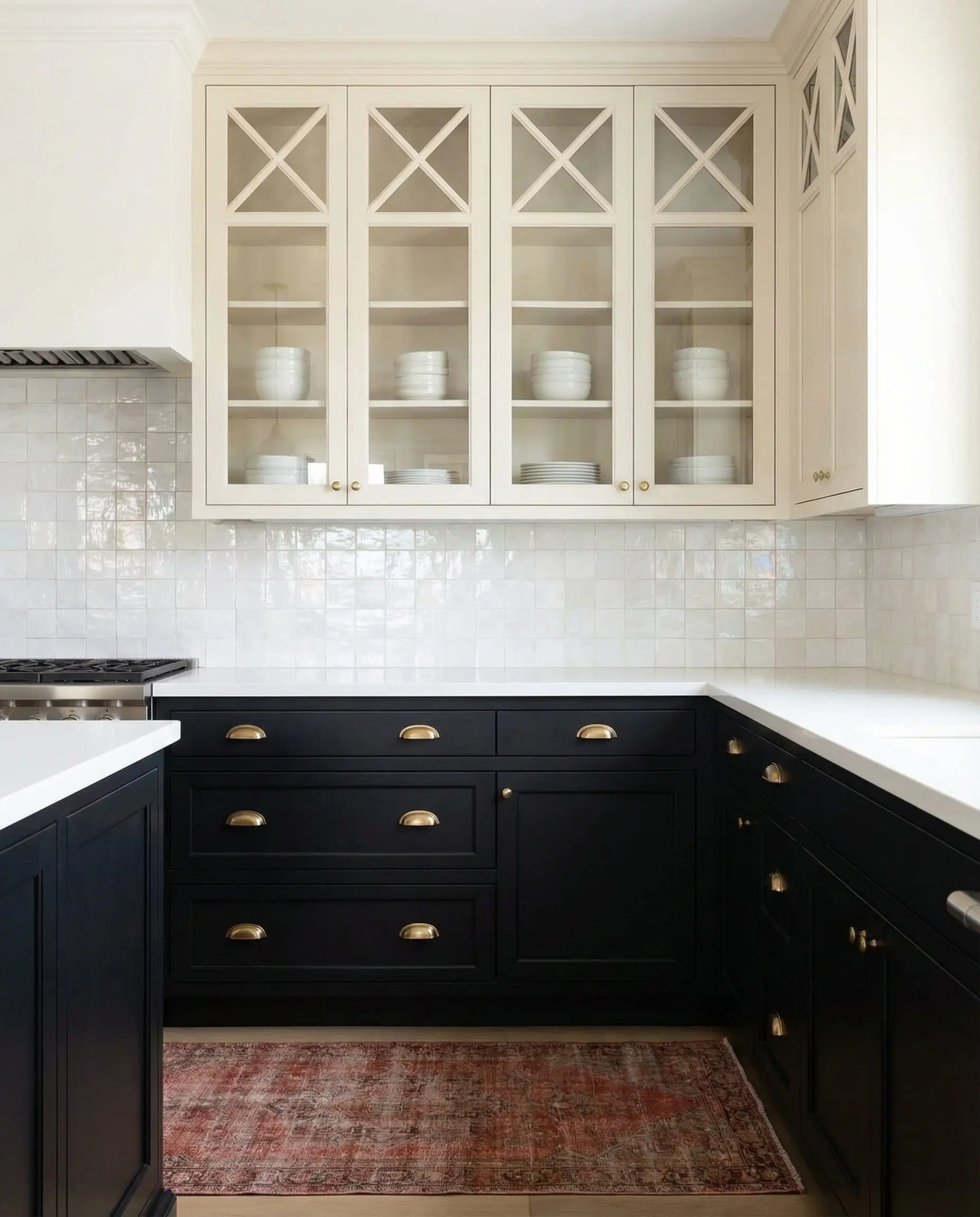 Transitional kitchen with matte black lower cabinets, creamy white glass-front upper cabinets, and a white zellige tile backsplash.