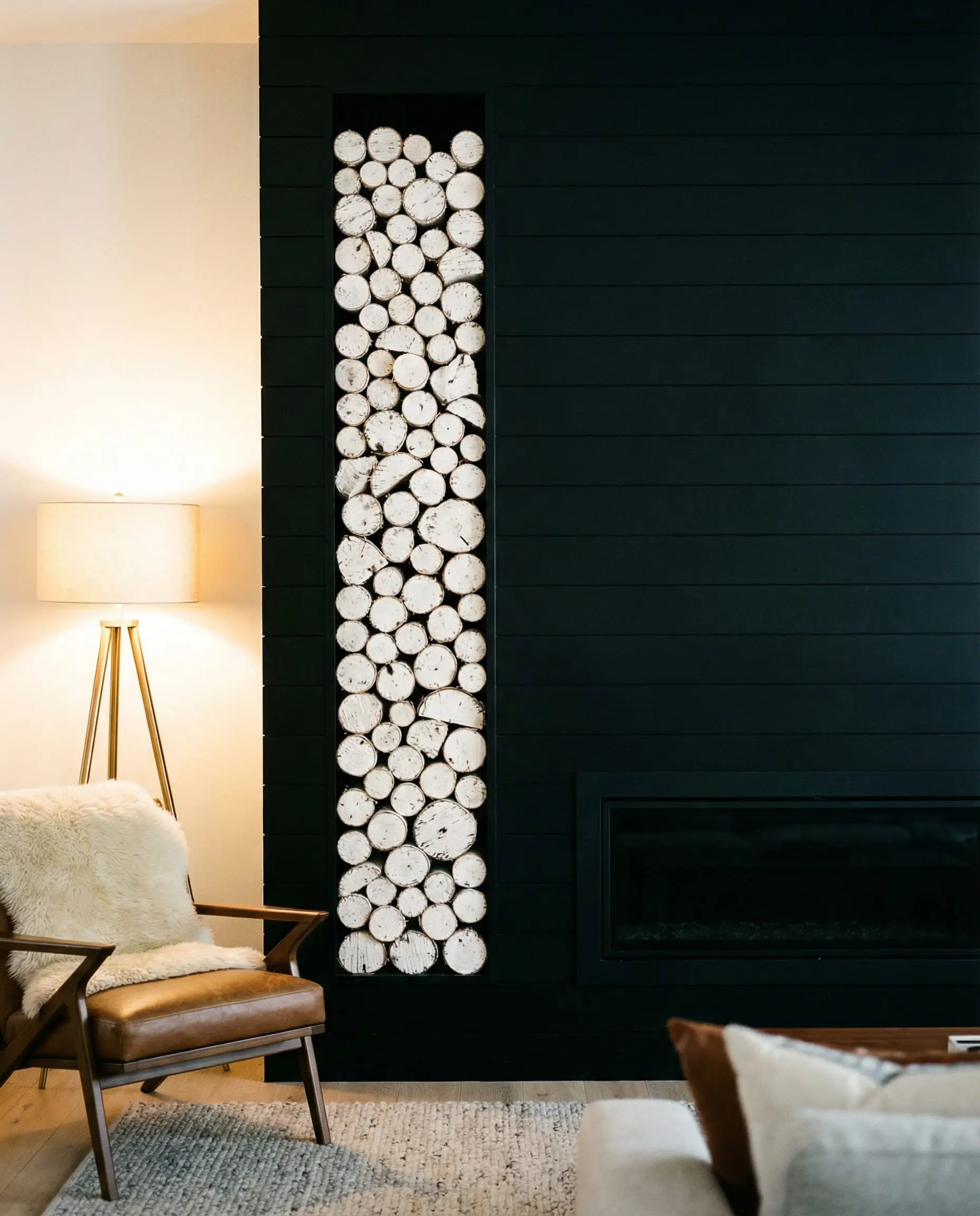 Modern black shiplap fireplace with a floor-to-ceiling vertical niche for log storage.