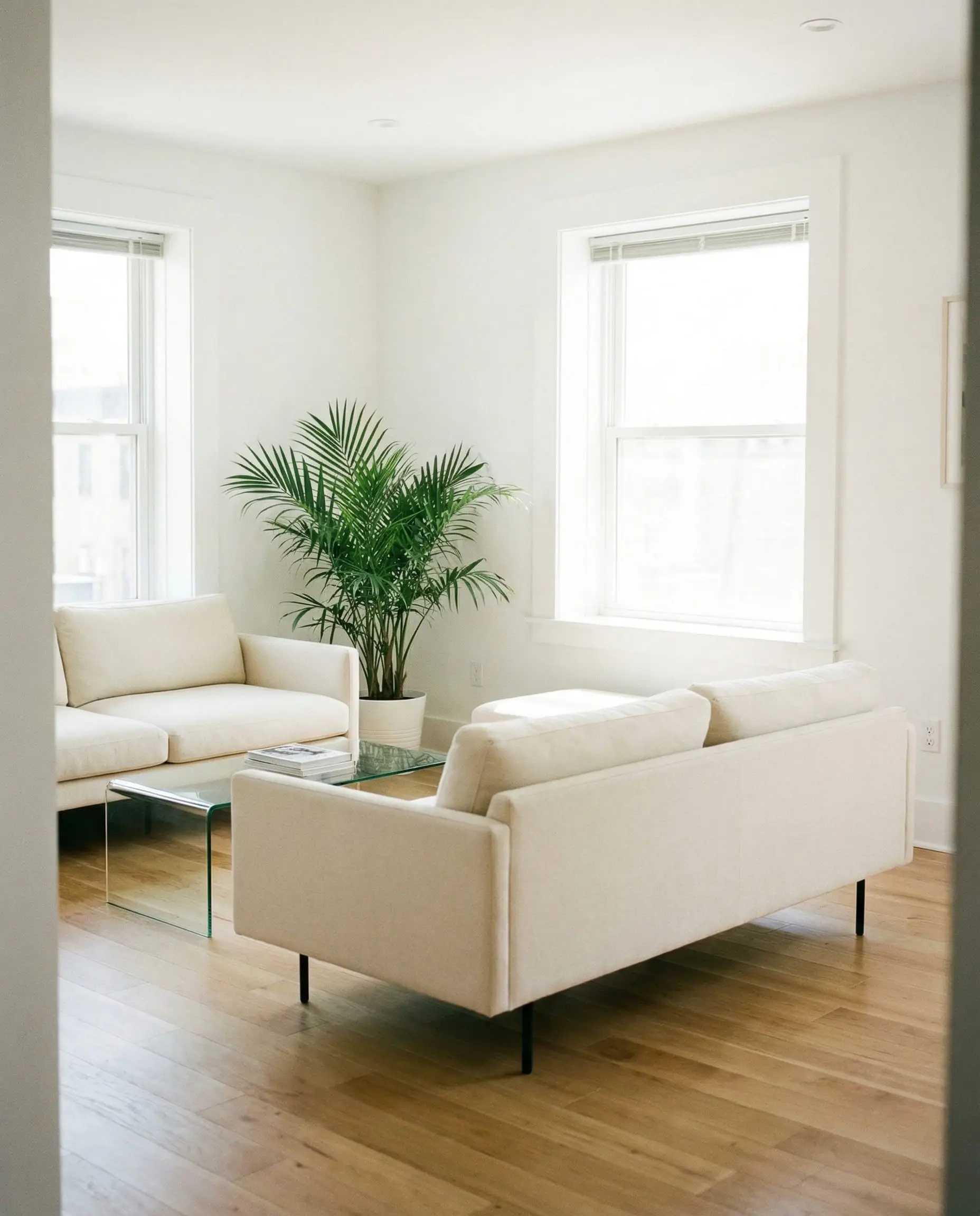 Modern white living room with sofas on thin metal legs, emphasizing the open floor space and airy feel.