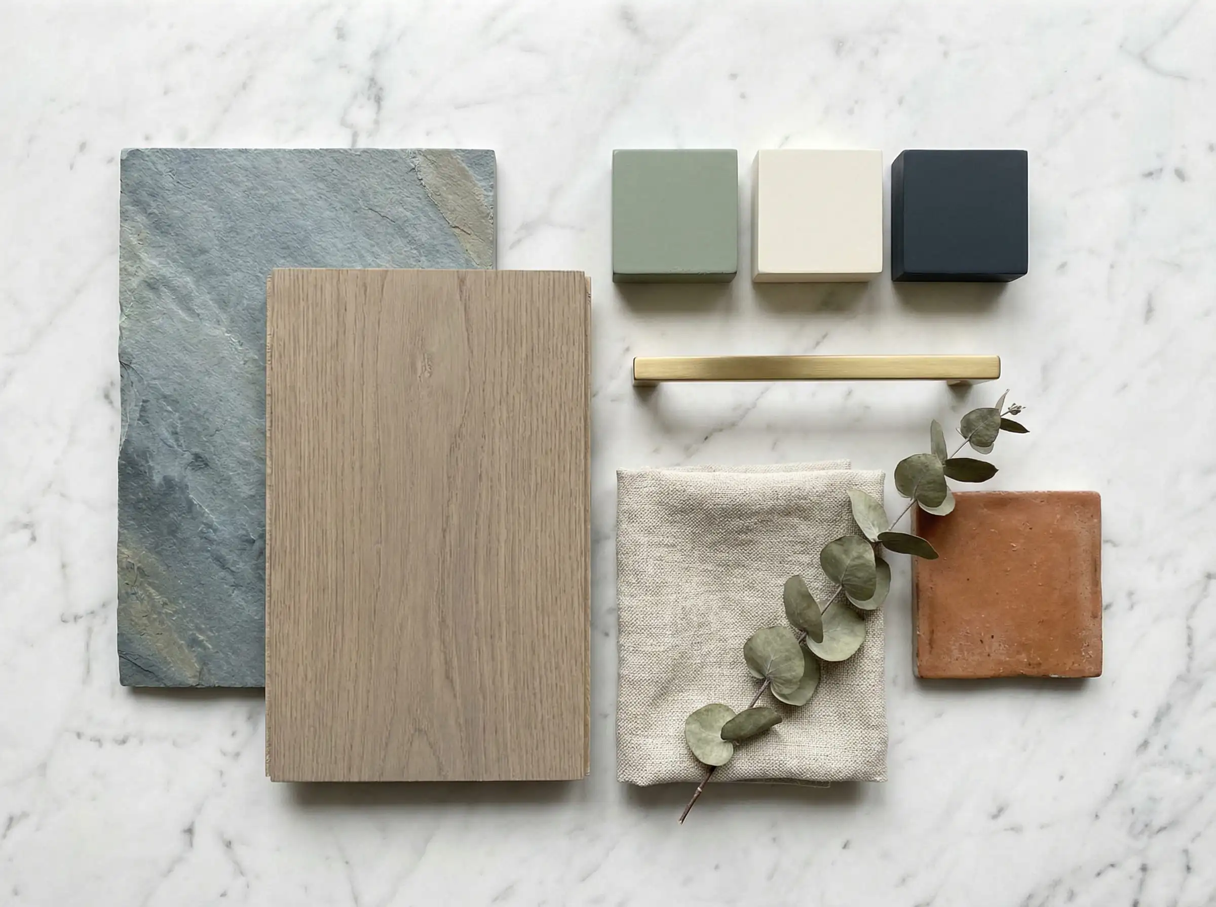 Interior design material flat-lay showing cool and warm gray flooring samples paired with trending paint blocks in creamy white, sage green, and navy blue.