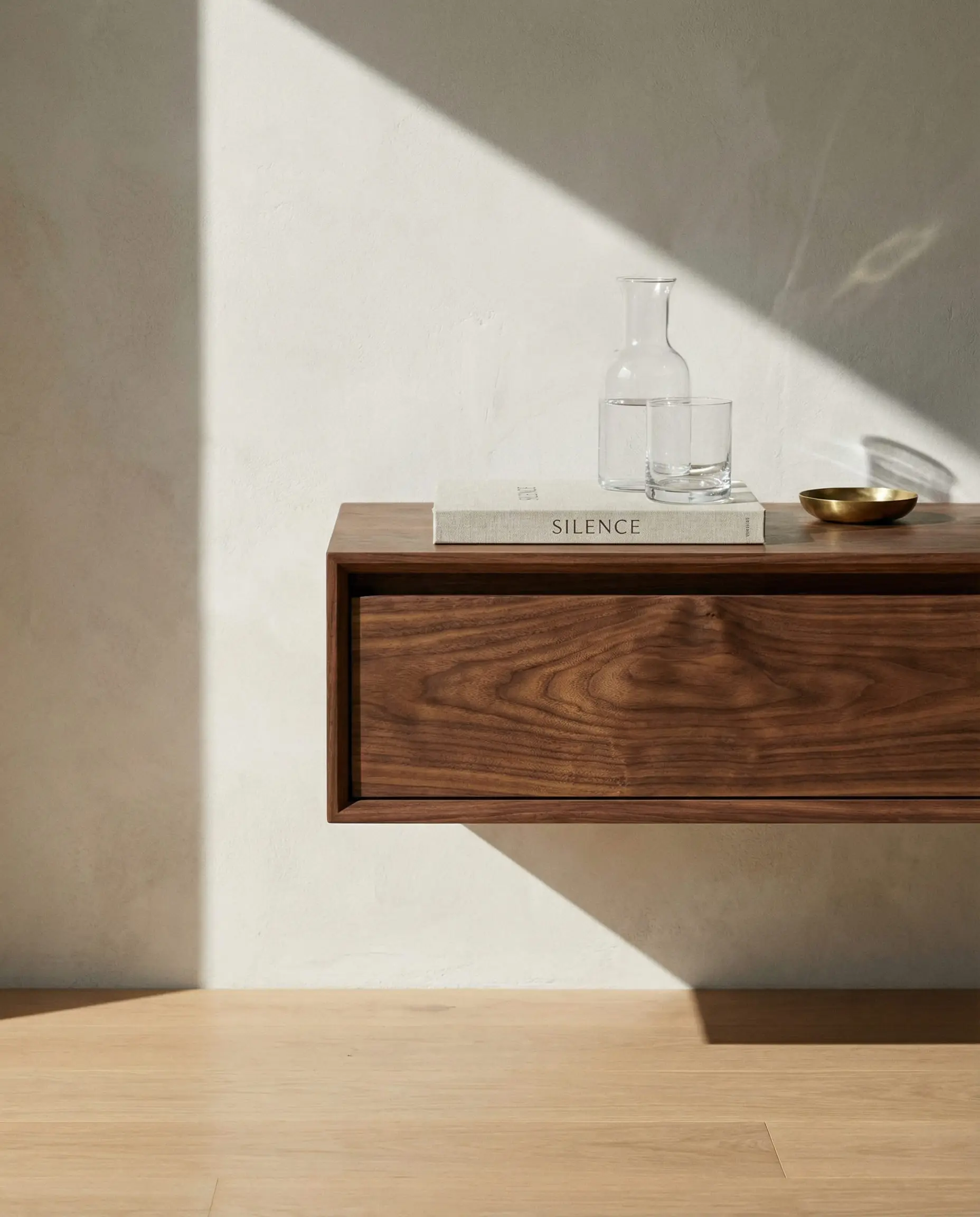 Walnut floating nightstand mounted on the wall to save floor space in a small bedroom.