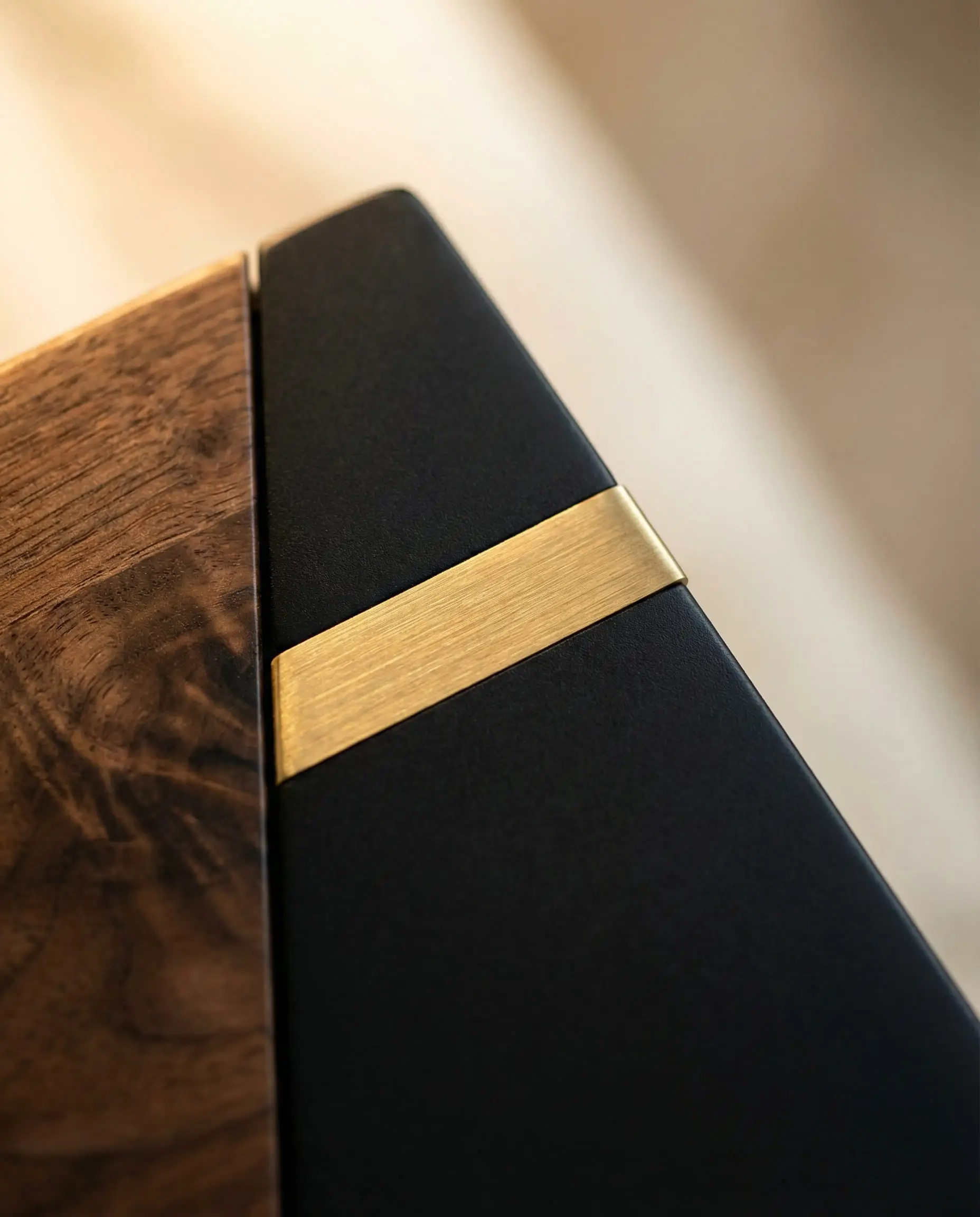 Close-up texture shot of American walnut wood grain contrasting with matte black metal and gold inlay.