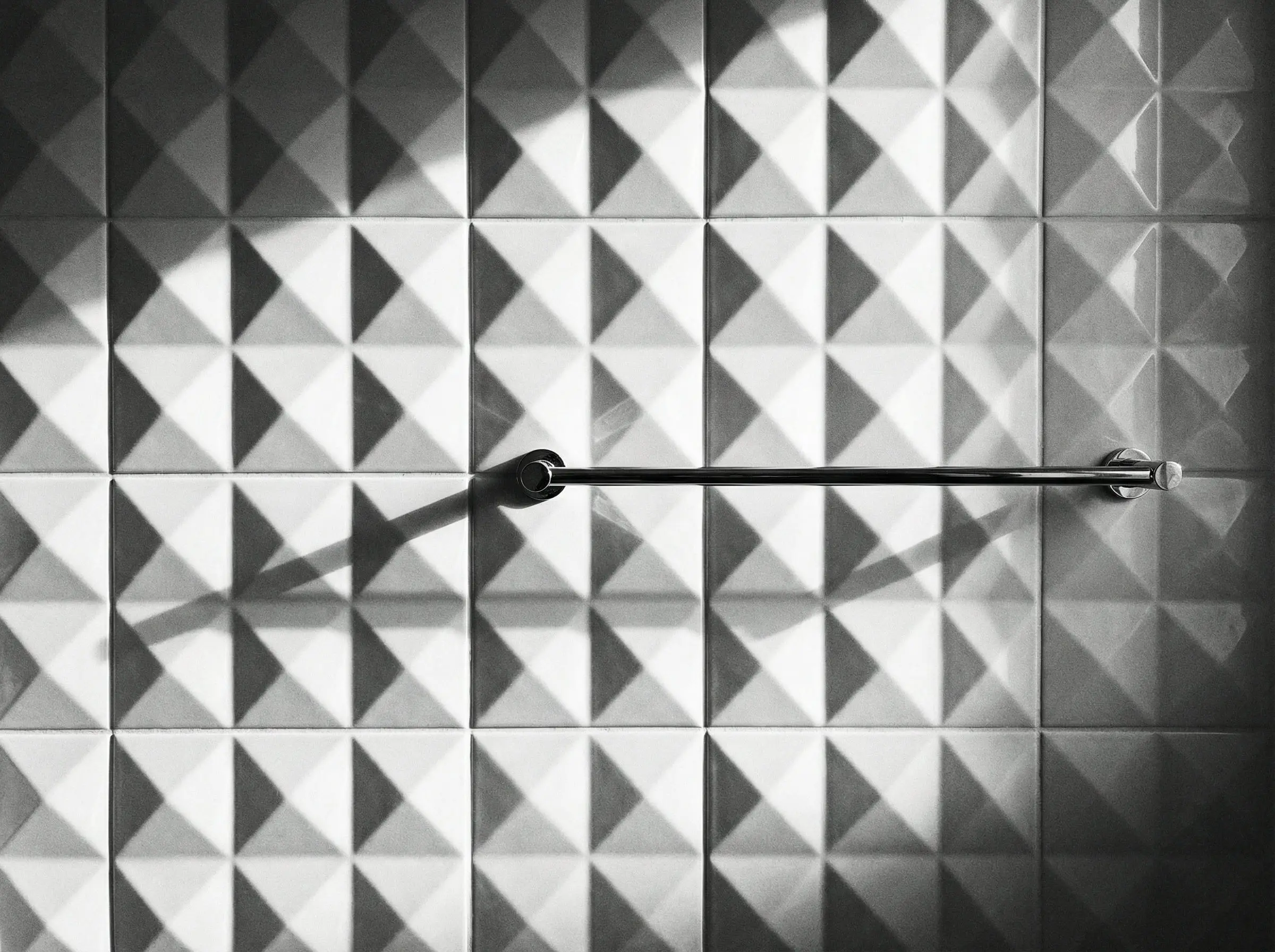 Close-up of white 3D pyramid tiles creating geometric shadows.