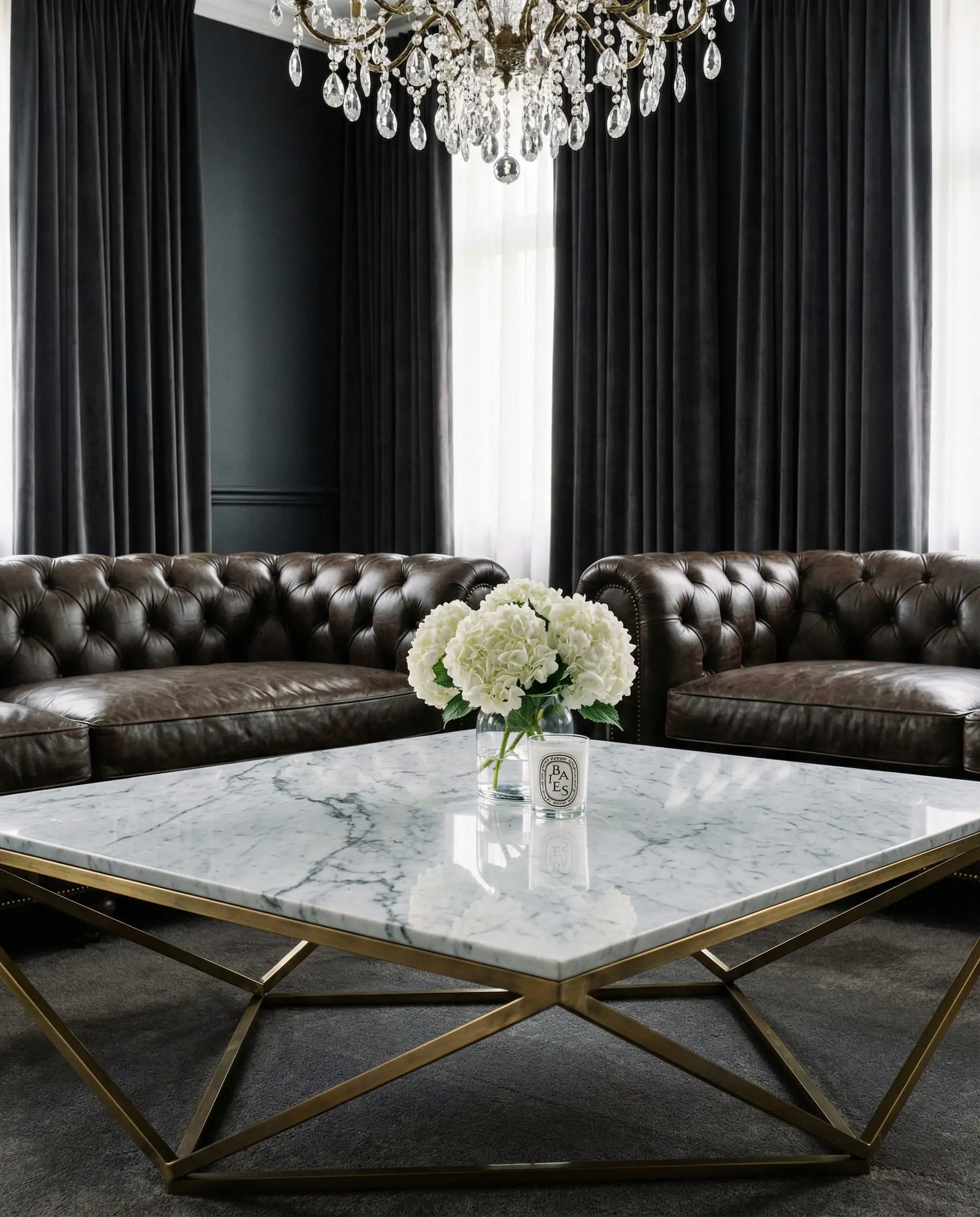 Luxurious white Carrara marble coffee table with a gold geometric base contrasting with a dark truffle brown leather Chesterfield.