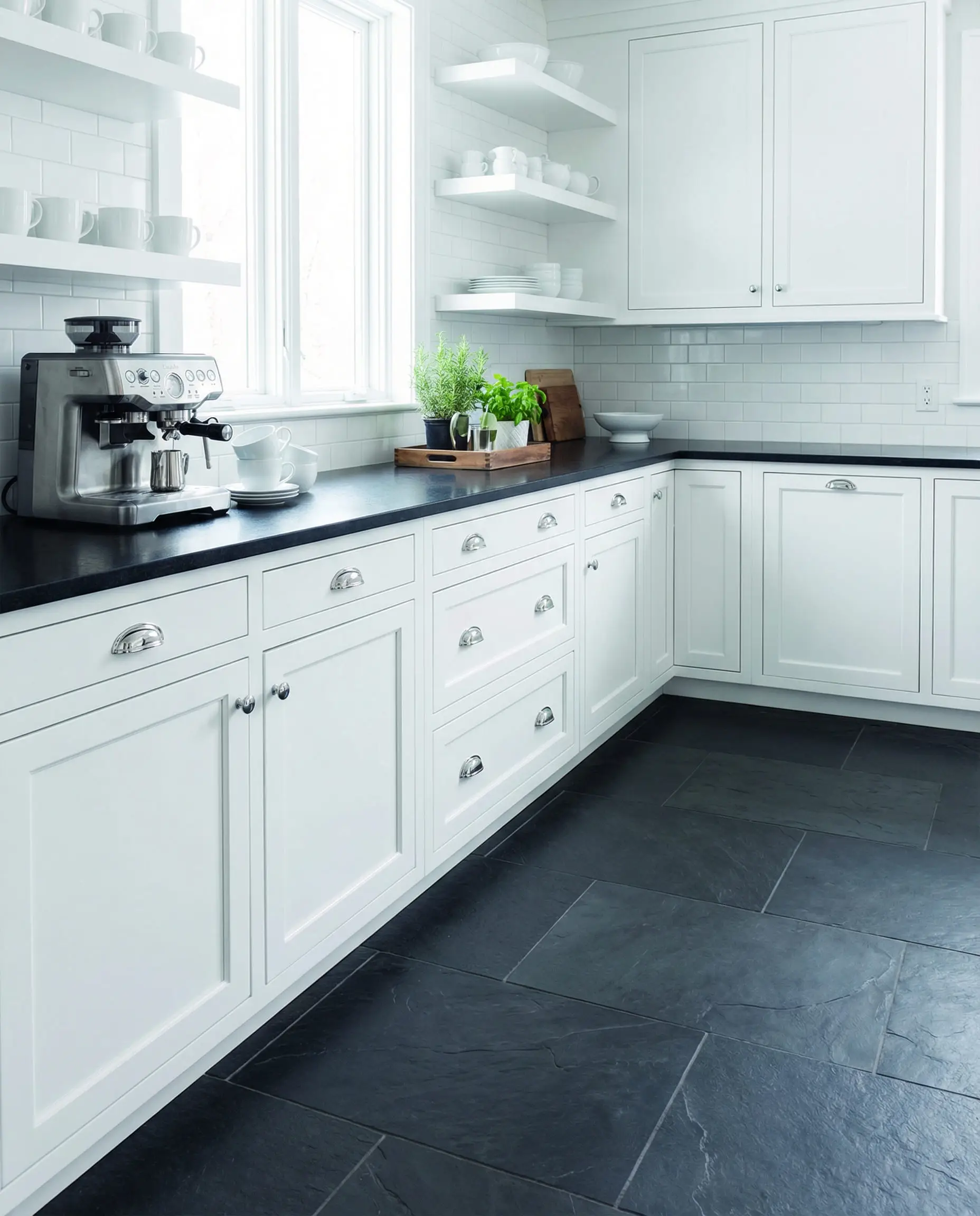 High-contrast kitchen featuring bright white shaker cabinets against dark charcoal gray slate flooring.