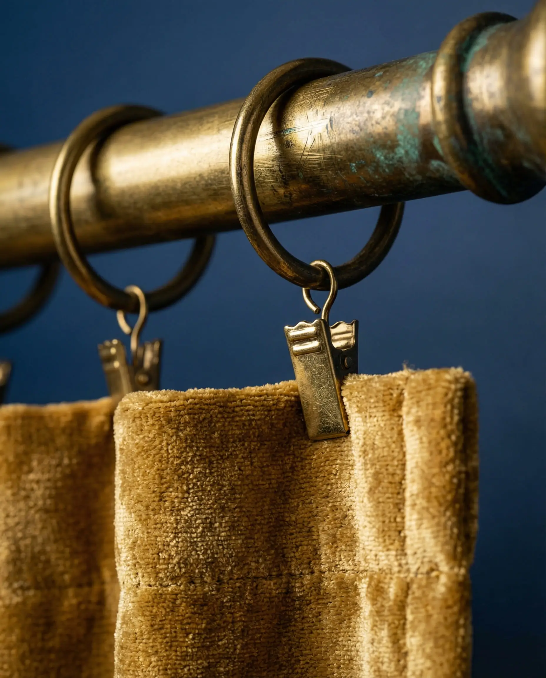 Close up of antique gold curtain hardware against a deep cobalt blue wall.