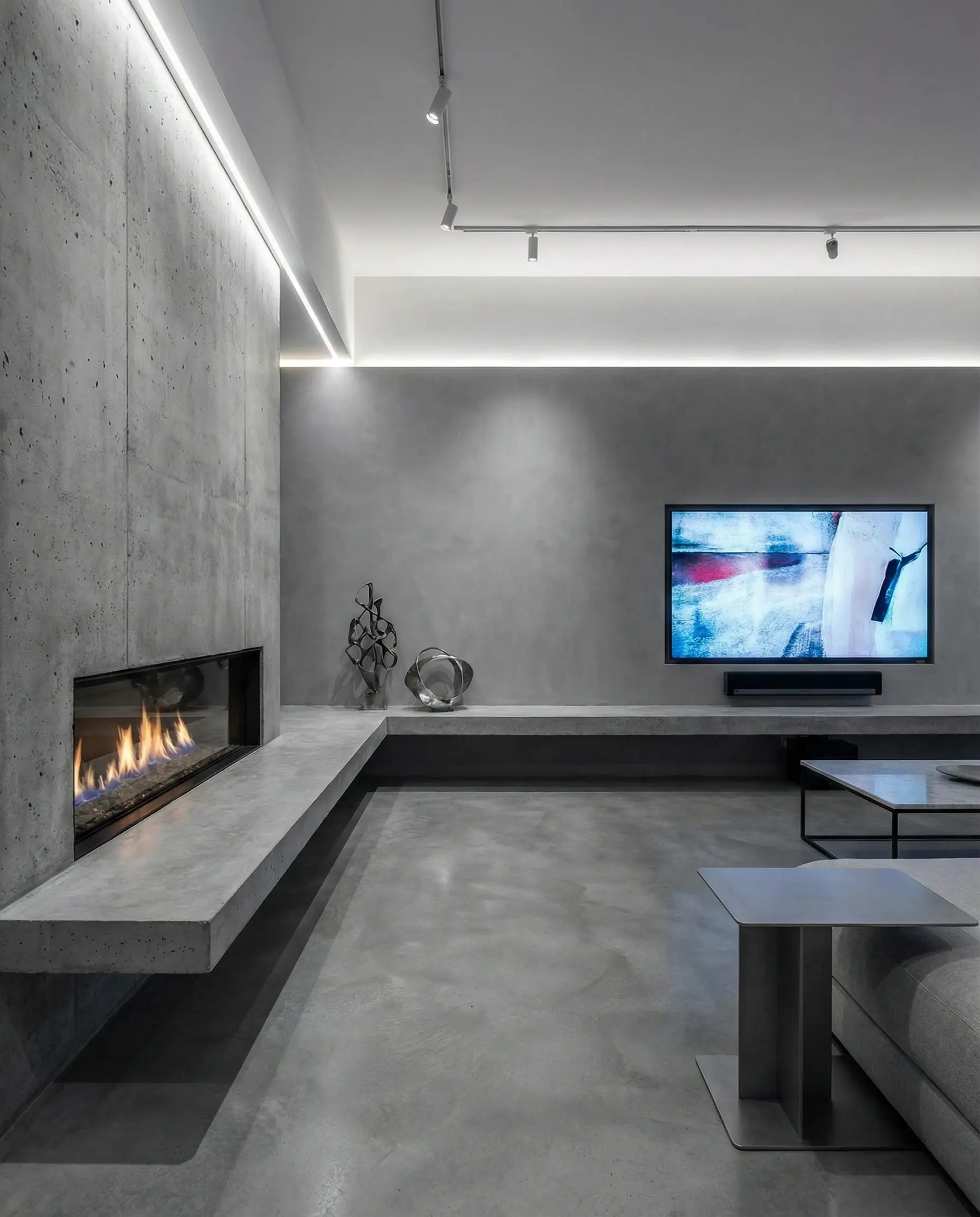 A long concrete wall featuring an asymmetrical layout with a fireplace on the left and a TV on the right, connected by a hearth.