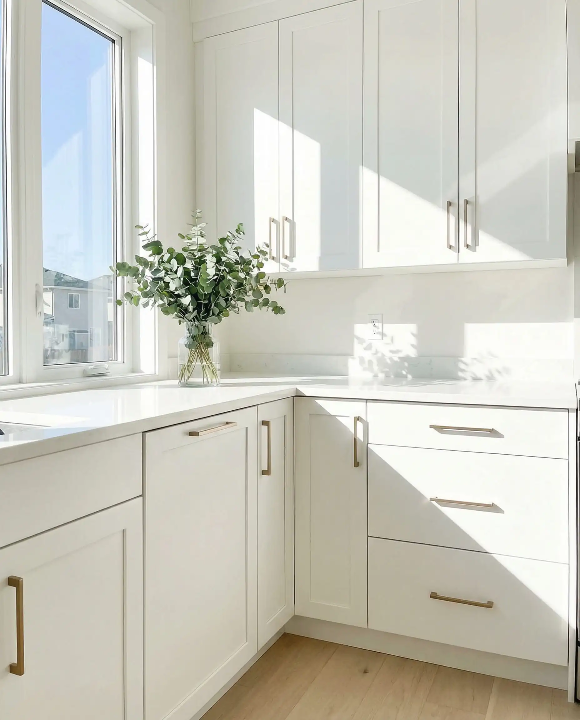 Bright modern kitchen with Benjamin Moore Chantilly Lace cabinets and champagne bronze hardware.