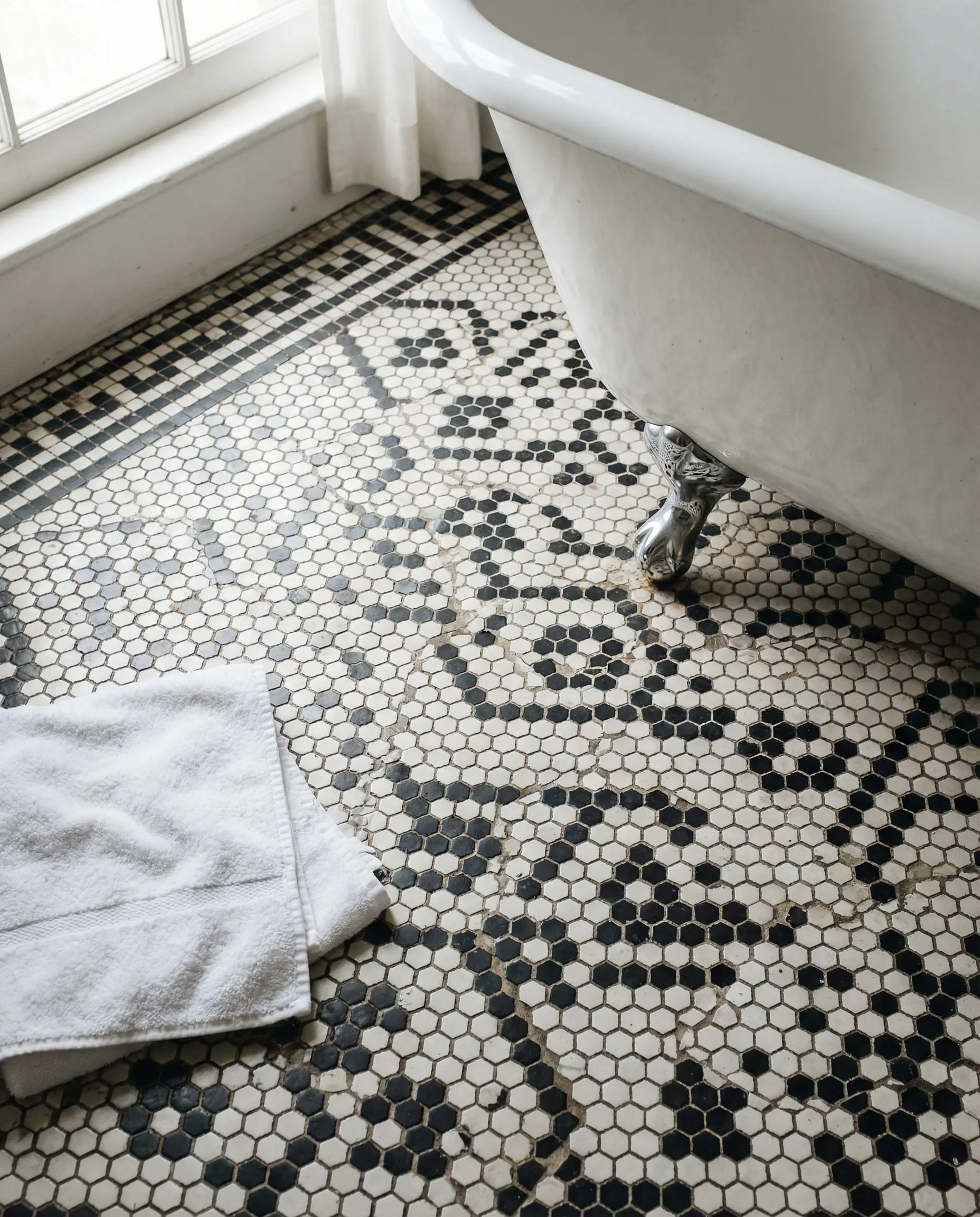 Top-down view of an intricate black and white mosaic tile floor in a classic Art Deco basketweave pattern.