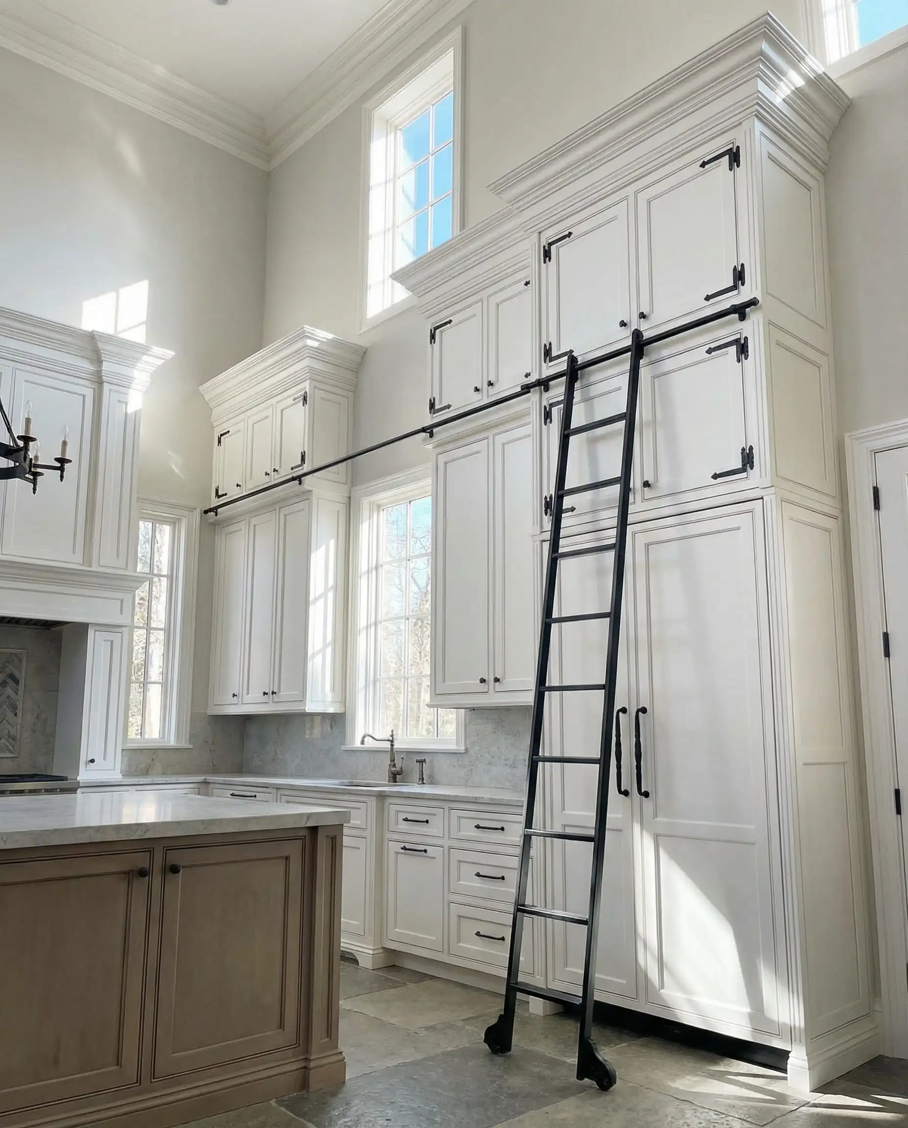 Low angle shot looking up at ceiling-height white cabinets with elaborate crown molding and grounding black hardware.
