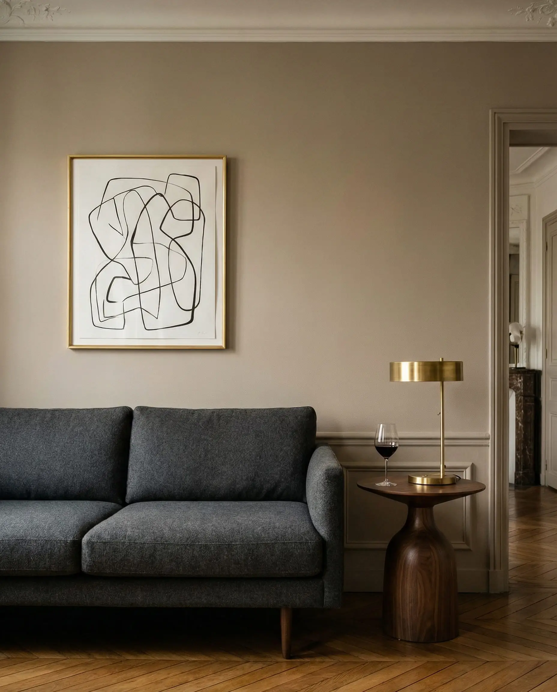Elegant Parisian-style living room with a dark charcoal grey wool sofa set against warm mushroom taupe walls painted in Farrow & Ball Jitney.
