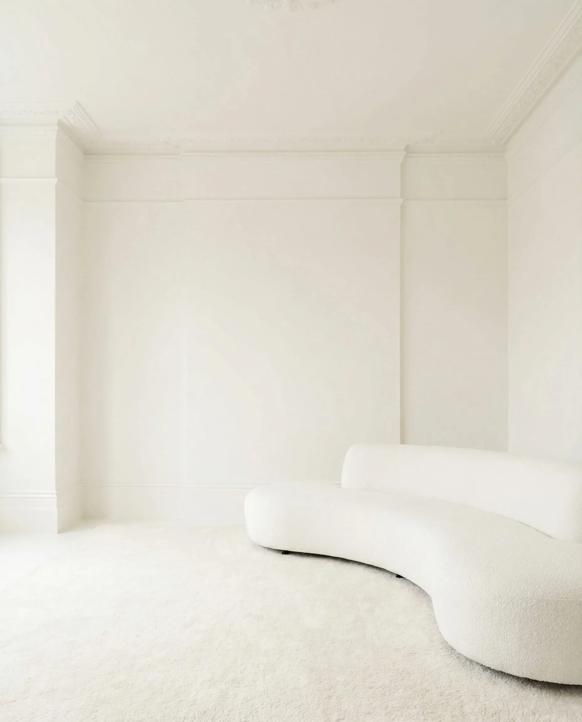 Minimalist living room where walls, ceiling, and trim are painted the exact same shade of warm white.