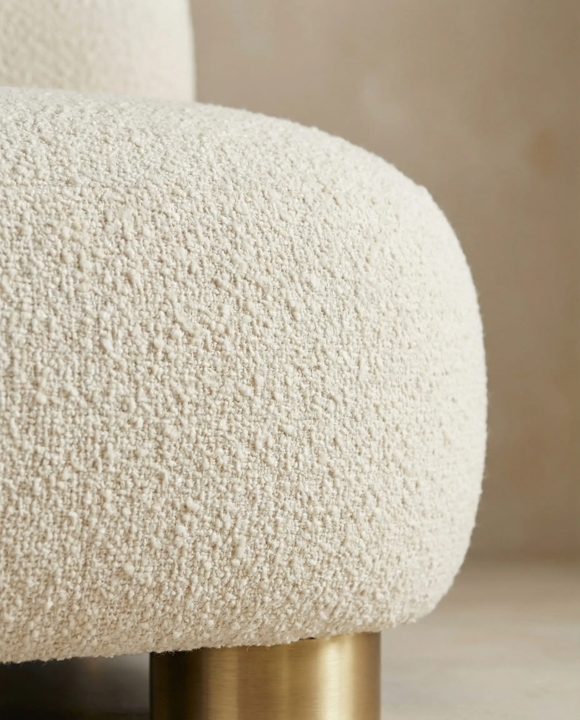 Close-up of a curved beige sofa upholstered in heavy textured bouclé fabric, highlighting the soft organic shapes of New Deco.