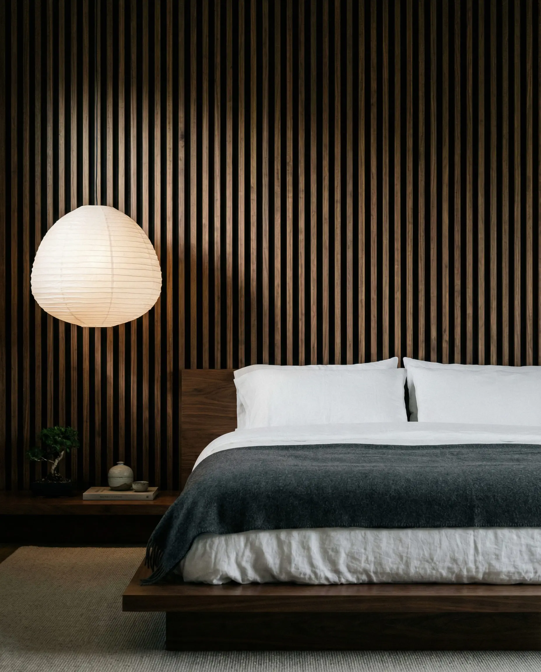 Bedroom featuring a dark walnut vertical wood slat accent wall behind a low profile bed.