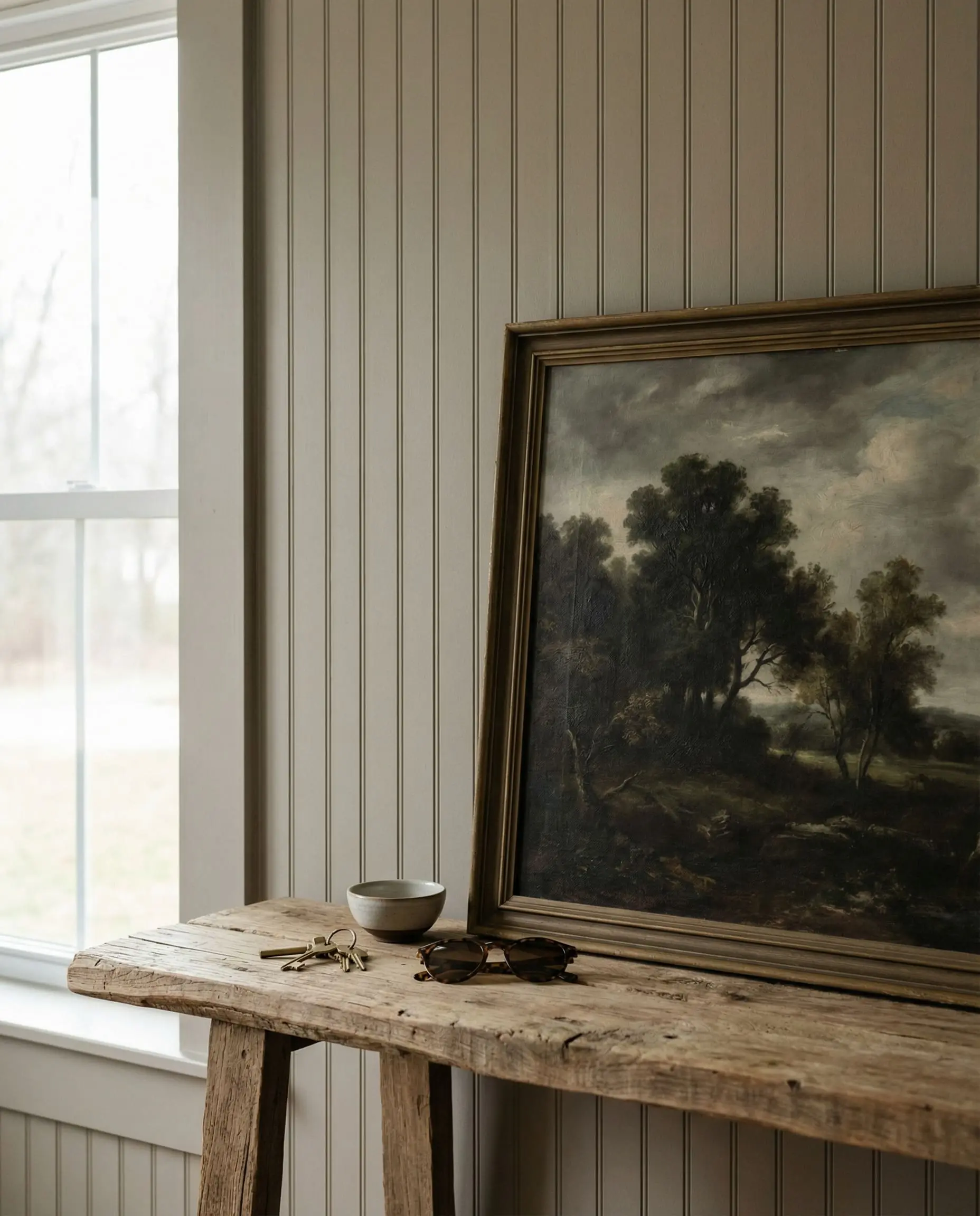 Warm greige vertical V-groove wall treatments highlight a raw-edge wood console and vintage art in this European farmhouse.