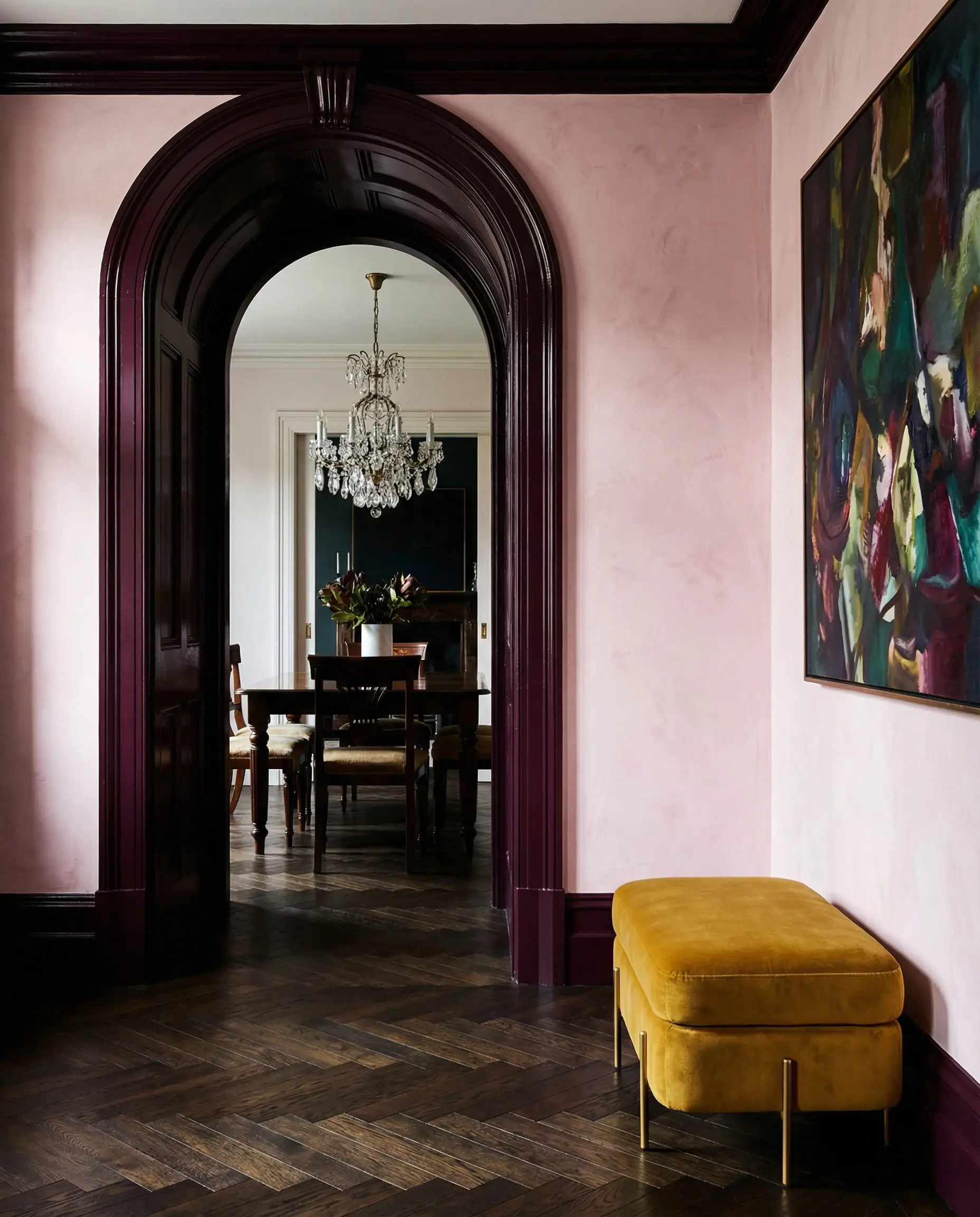 Arched doorway painted in glossy Farrow & Ball Brinjal burgundy against warm white walls.