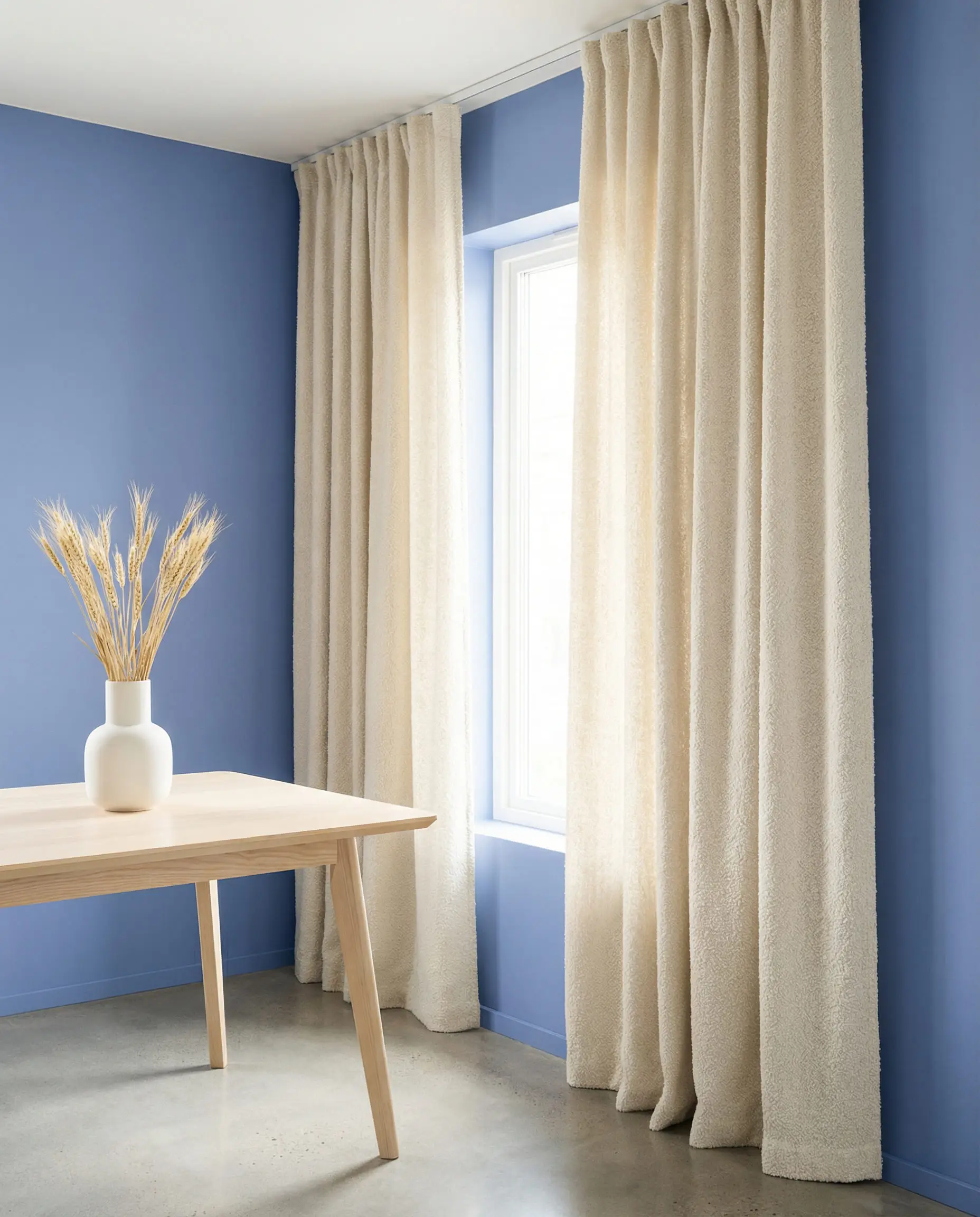 Modern dining room with french blue walls and cream bouclé curtains.