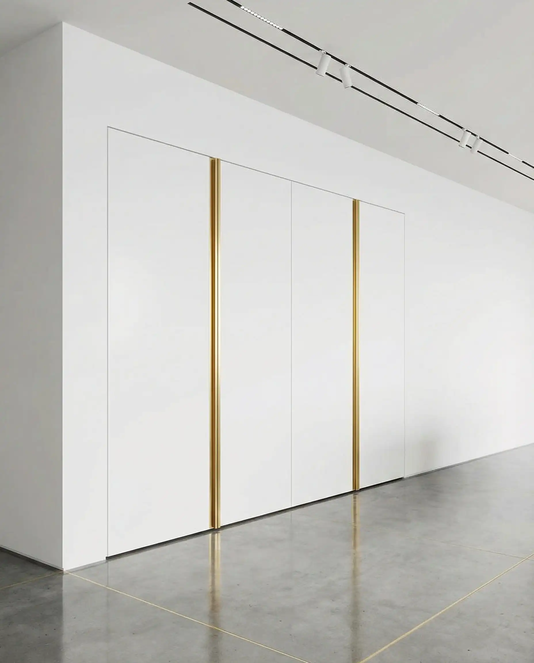 Integrated white pantry doors with tall vertical gold handles in a minimalist kitchen.