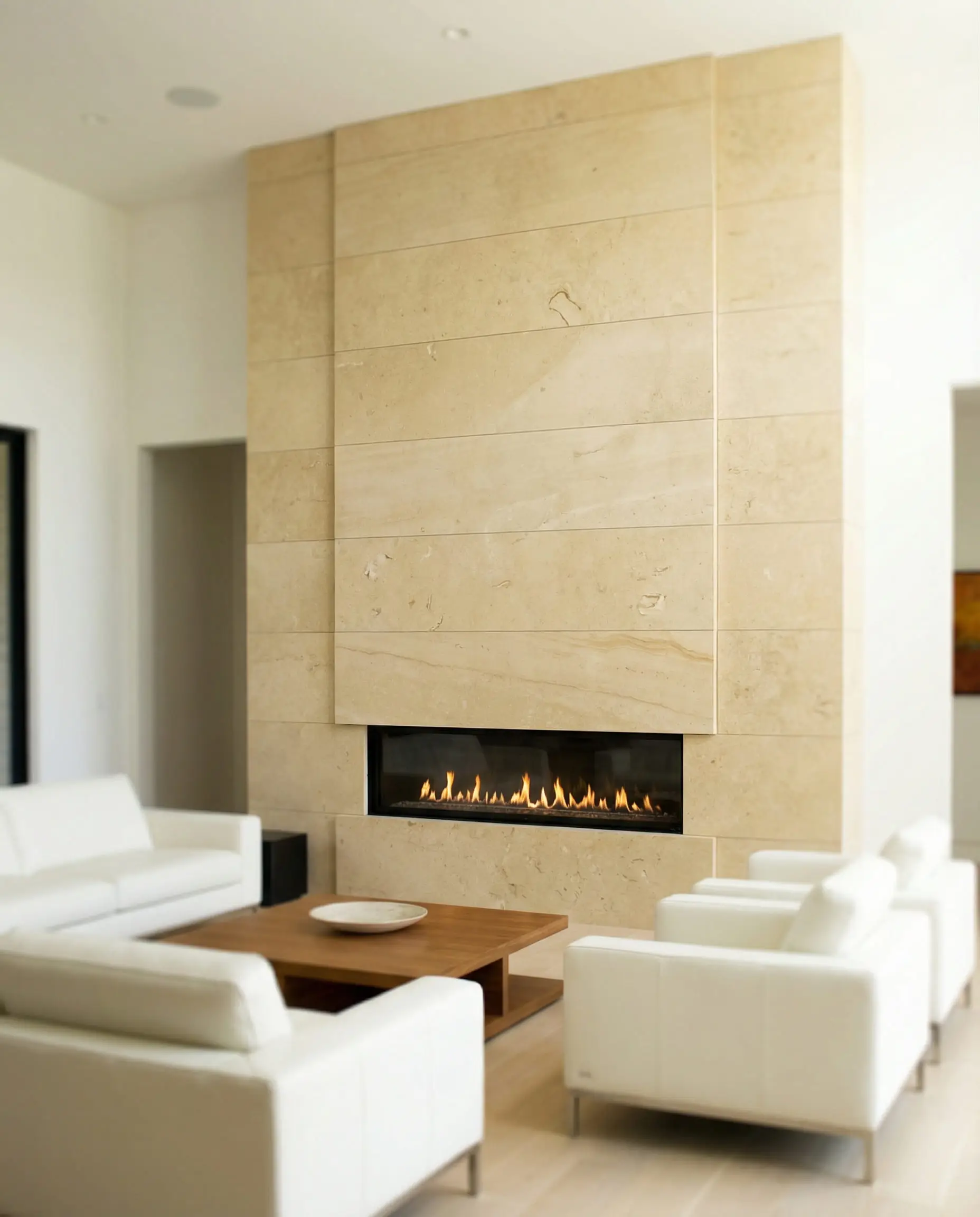 A modern fireplace clad in large, smooth honed limestone slabs in a creamy beige tone for a spa-like aesthetic.