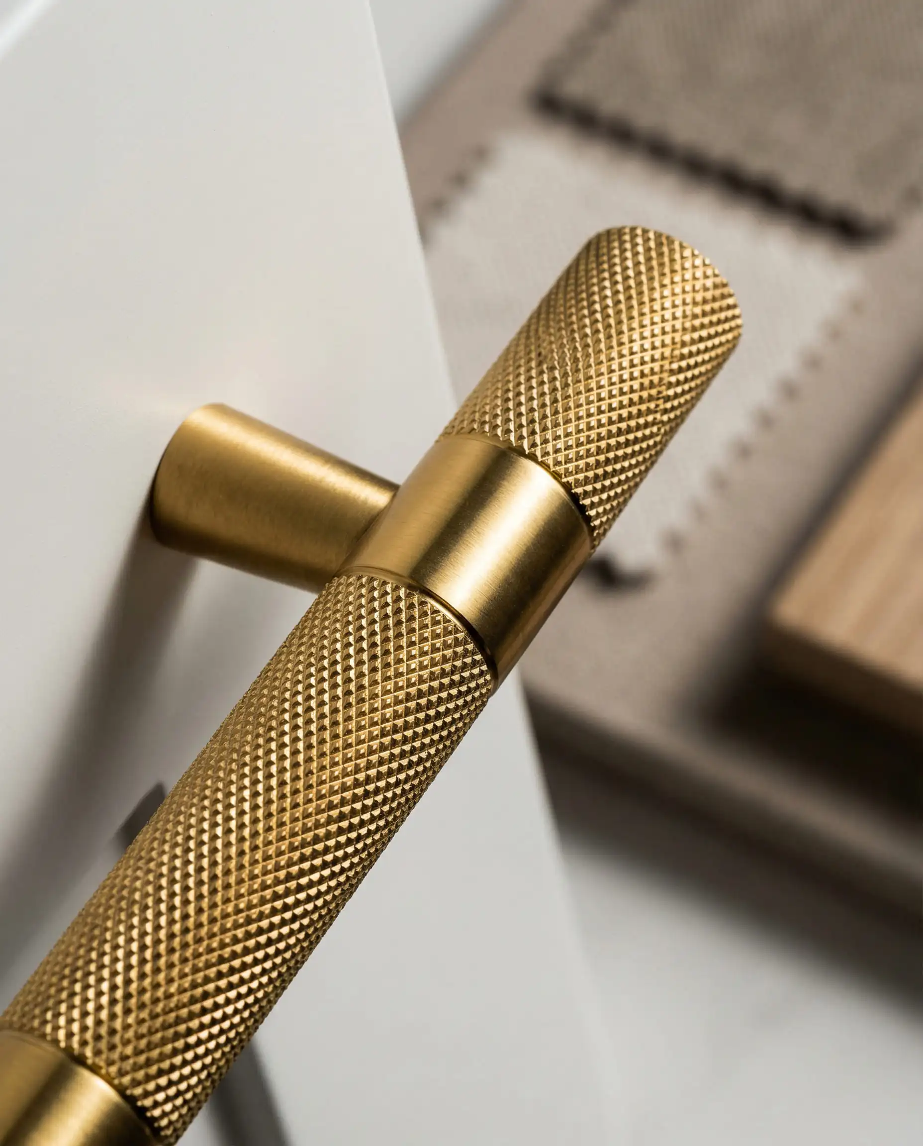 Macro shot of a knurled gold T-bar cabinet pull showing diamond-cut texture.
