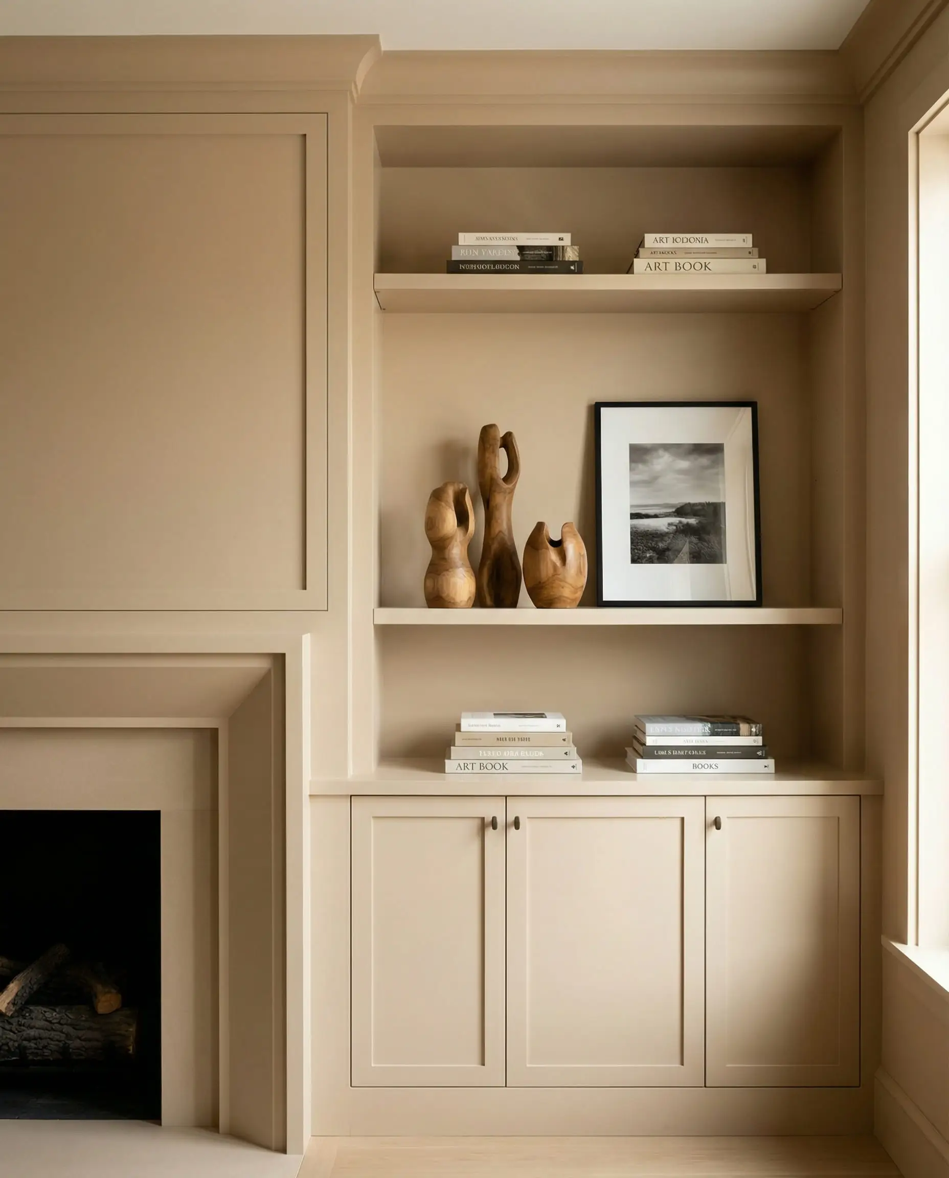 Symmetrical built-in shelving painted warm beige flanking a central fireplace.