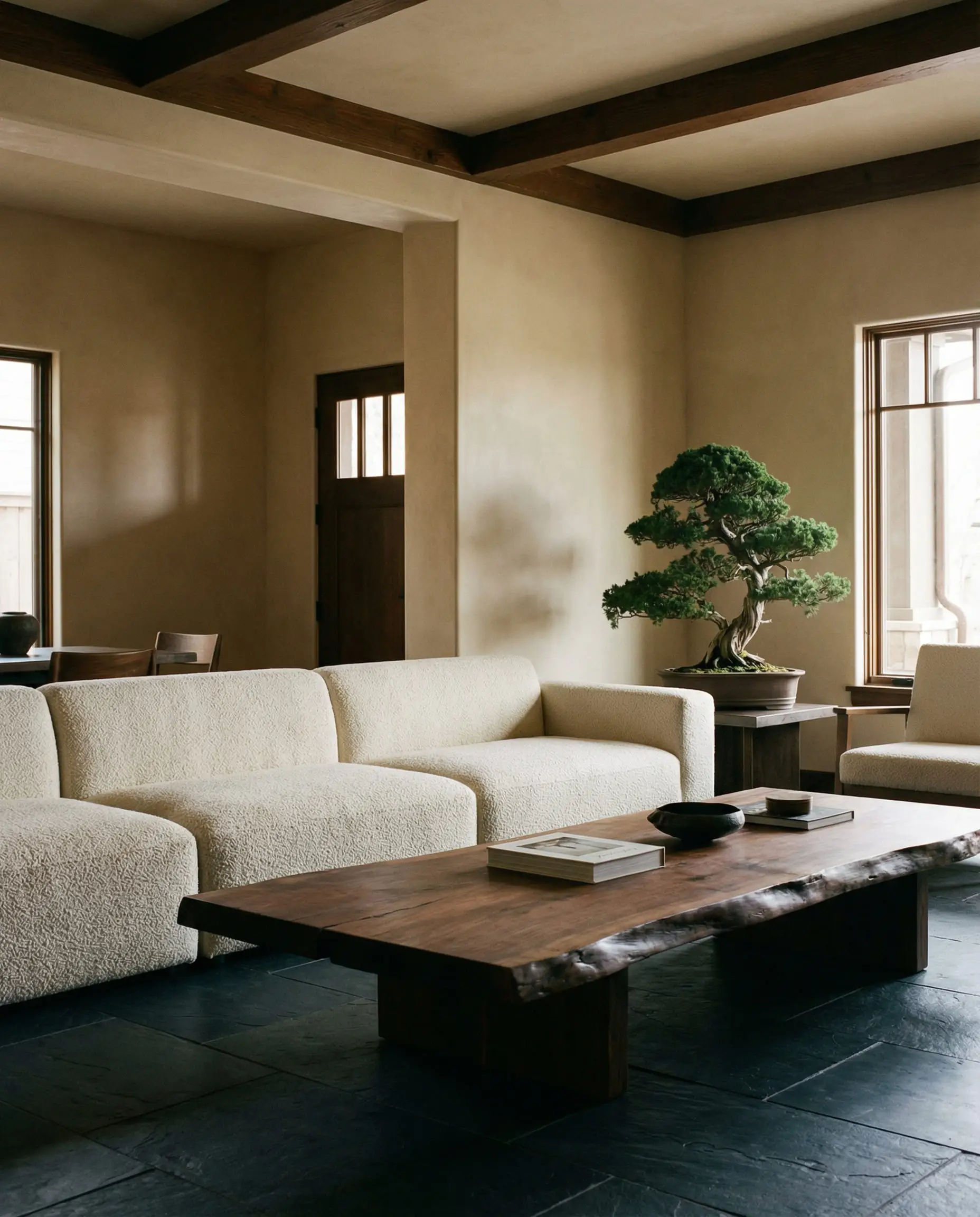 Cream boucle sofa with a low profile silhouette sitting on a slate floor in a minimalist craftsman room.