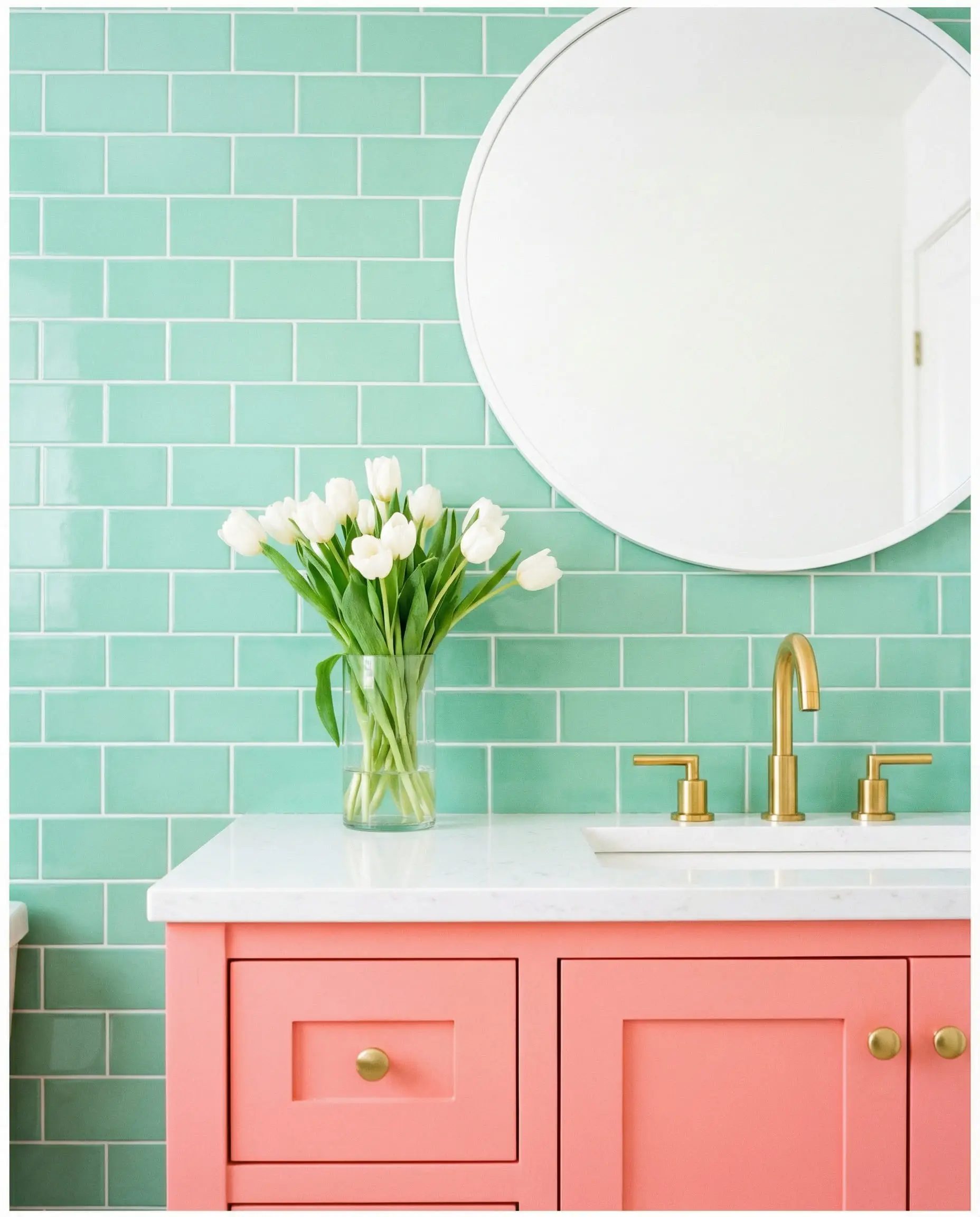 Playful bathroom vanity with mint green subway tiles, a coral pink cabinet, and polished gold hardware.