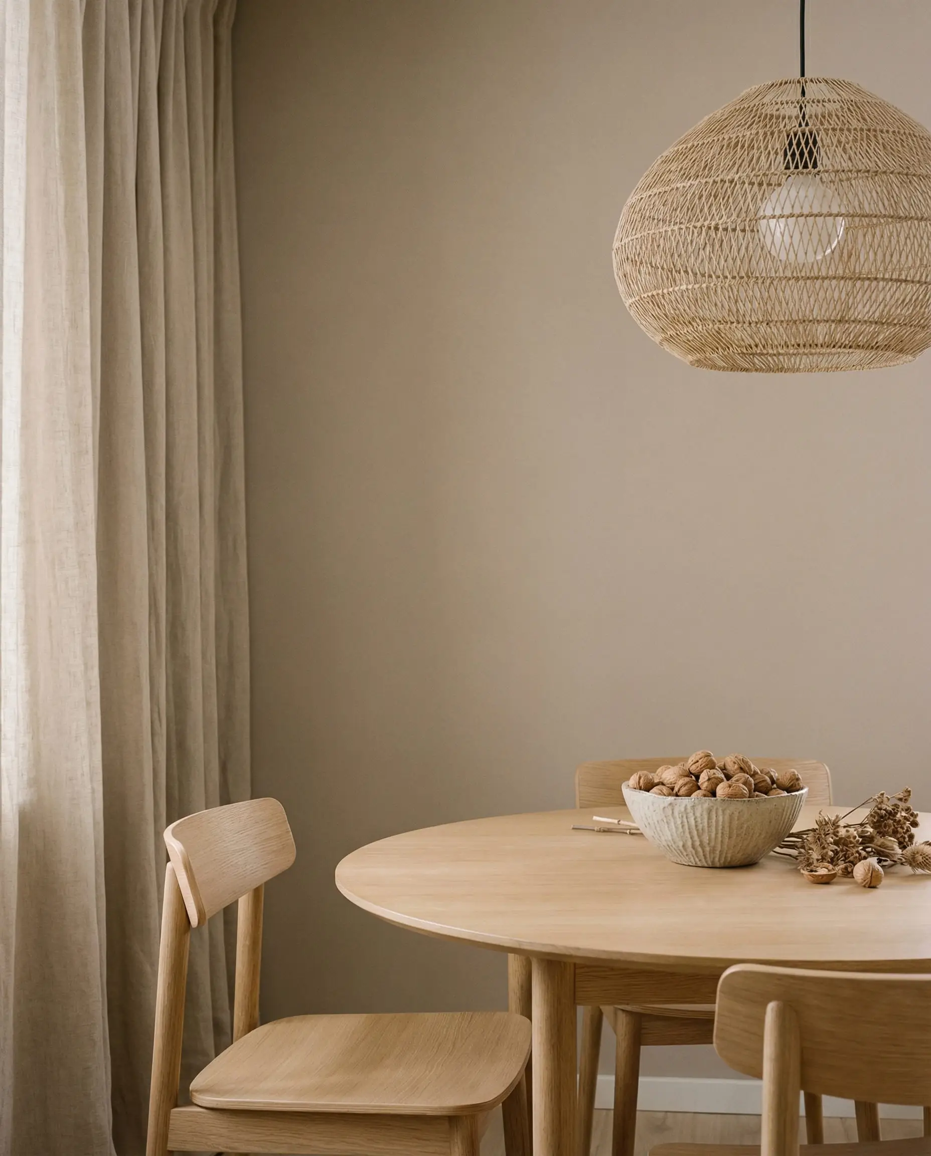 Minimalist dining room painted in warm mushroom taupe with beige linen curtains and tone-on-tone furniture.