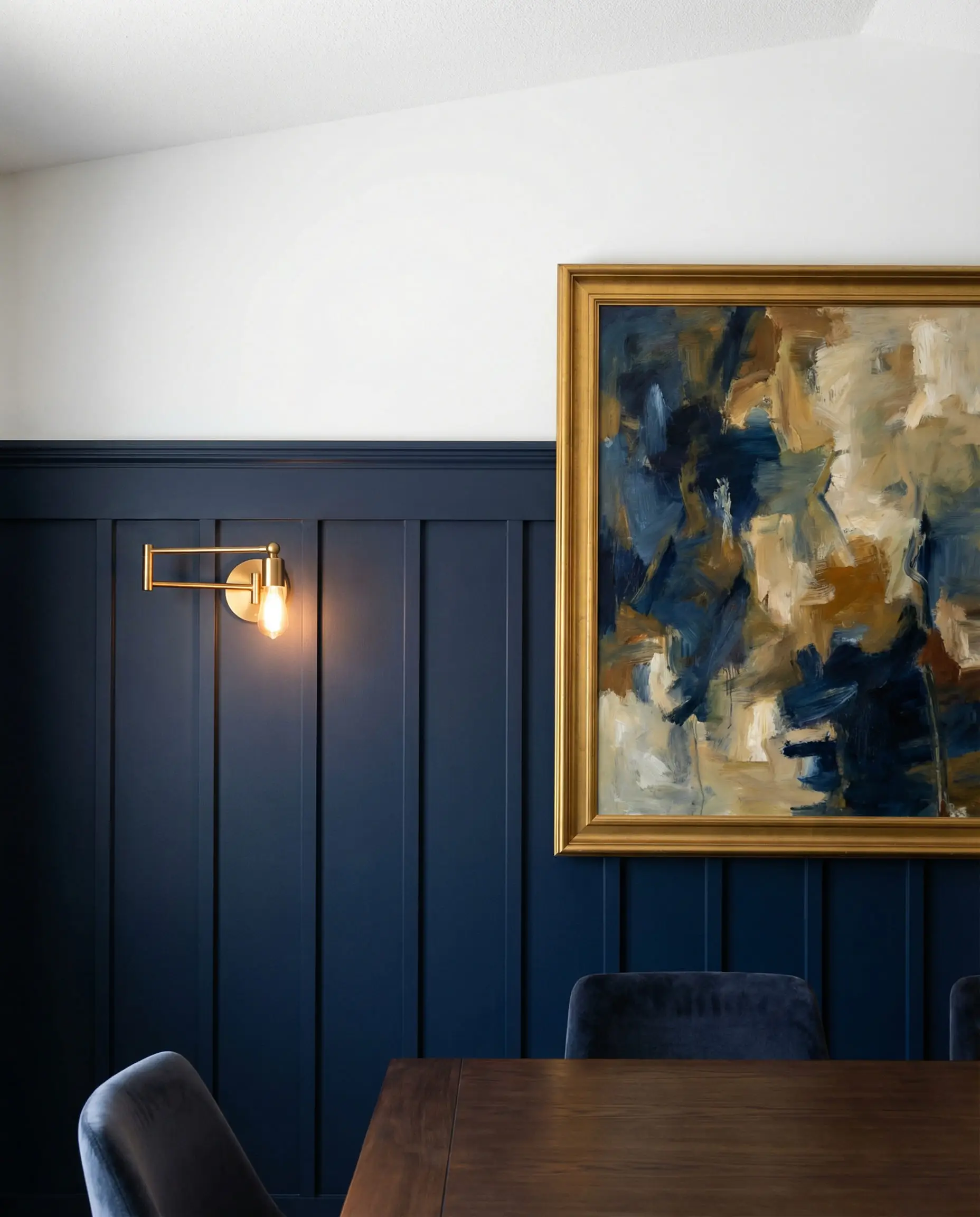 Dining room wall with navy blue board and batten wainscoting on the bottom two-thirds.