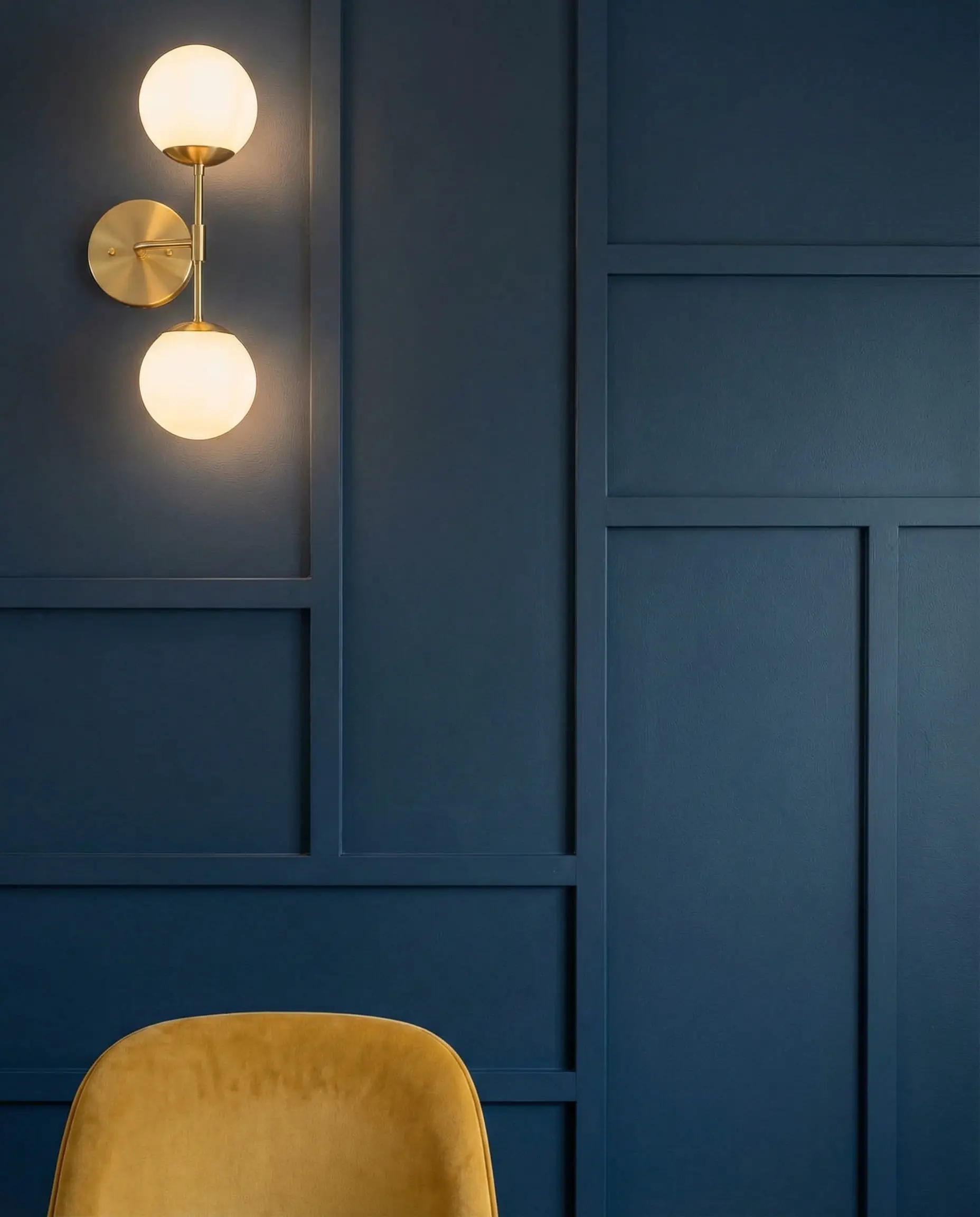 Modern dining room with an asymmetrical geometric board and batten accent wall painted in deep Hale Navy with gold sconces.