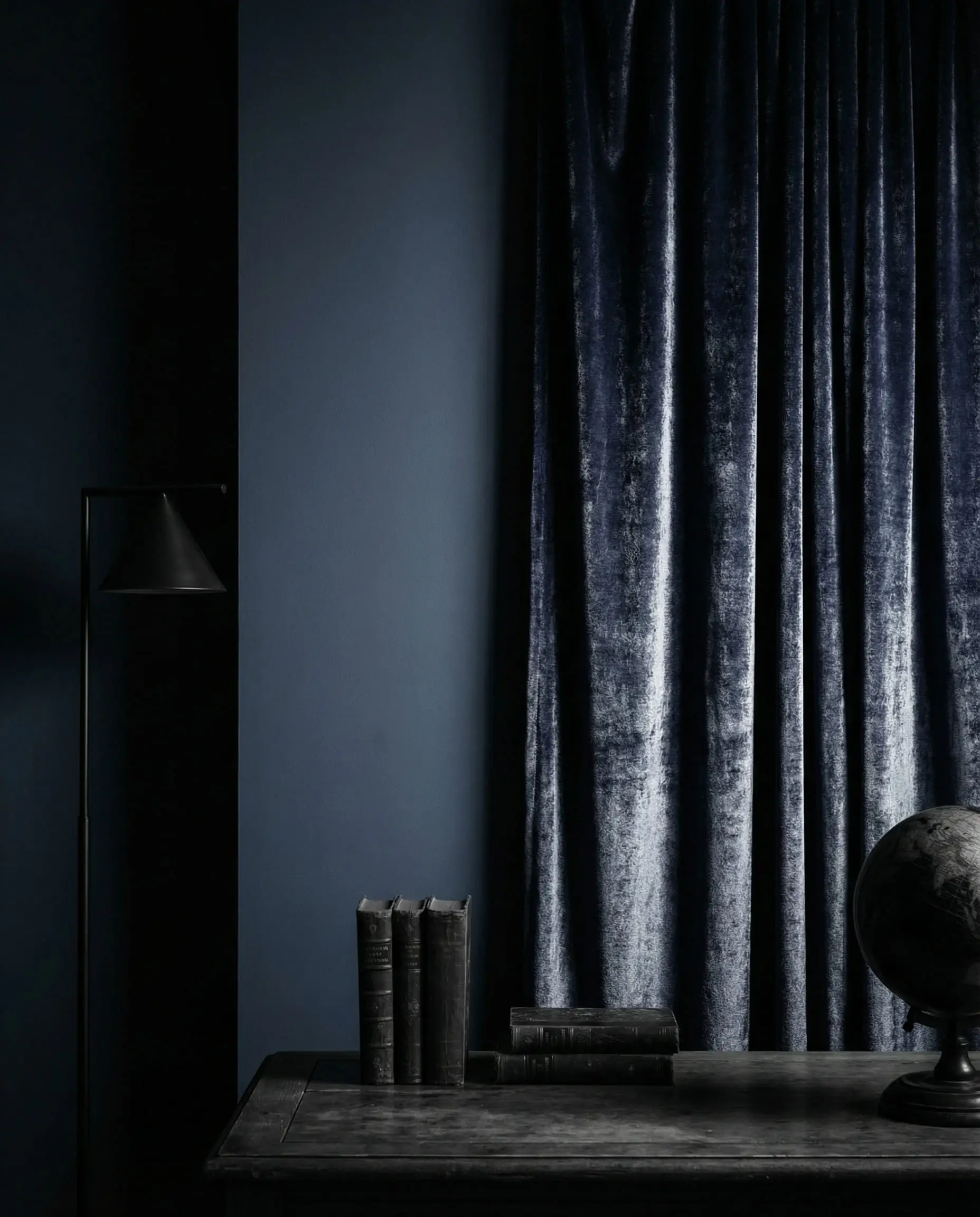 Monochromatic navy blue wall paired with matching navy velvet curtains highlighting texture difference.