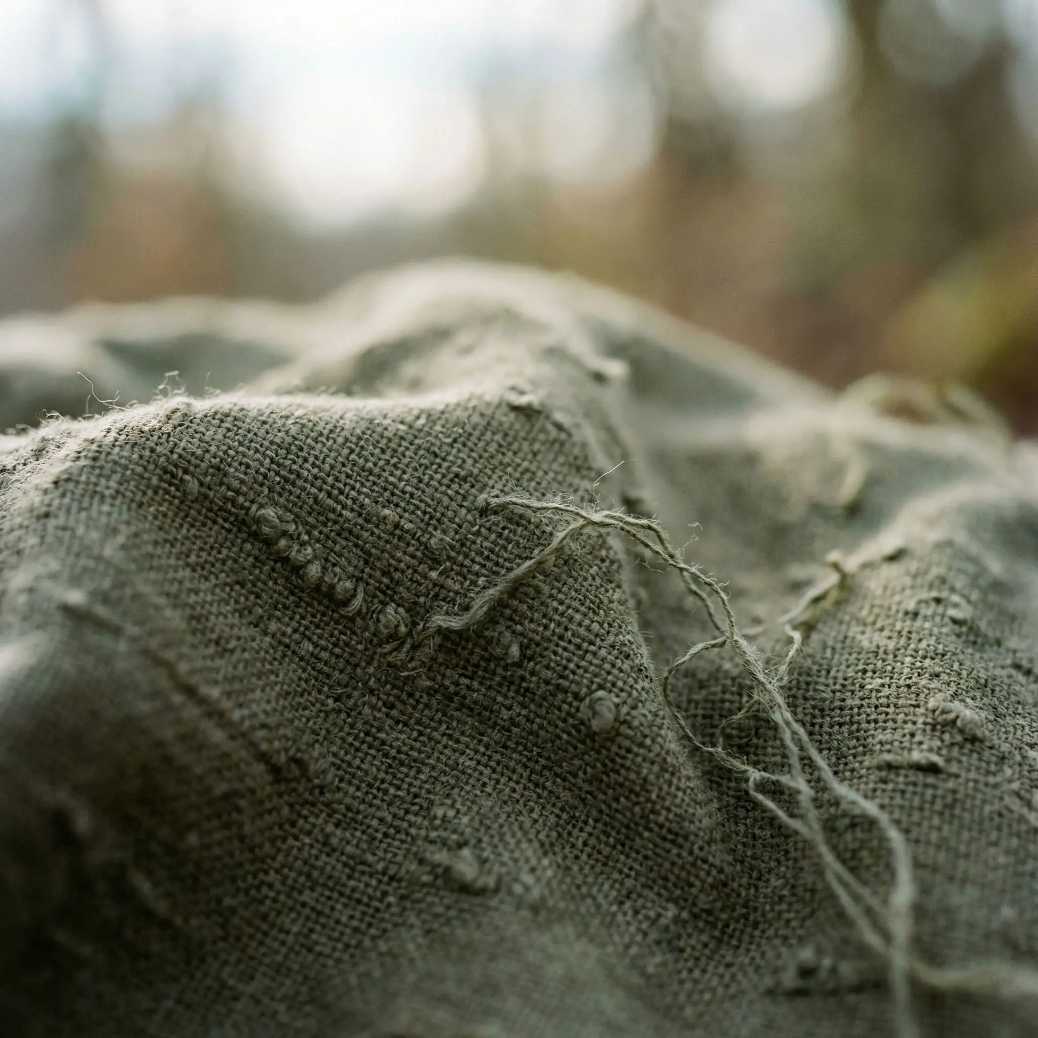 Thick, nubby heavyweight slub linen fabric in a muddy olive green tone emphasizes the tactile natural materials used in modern organic style.