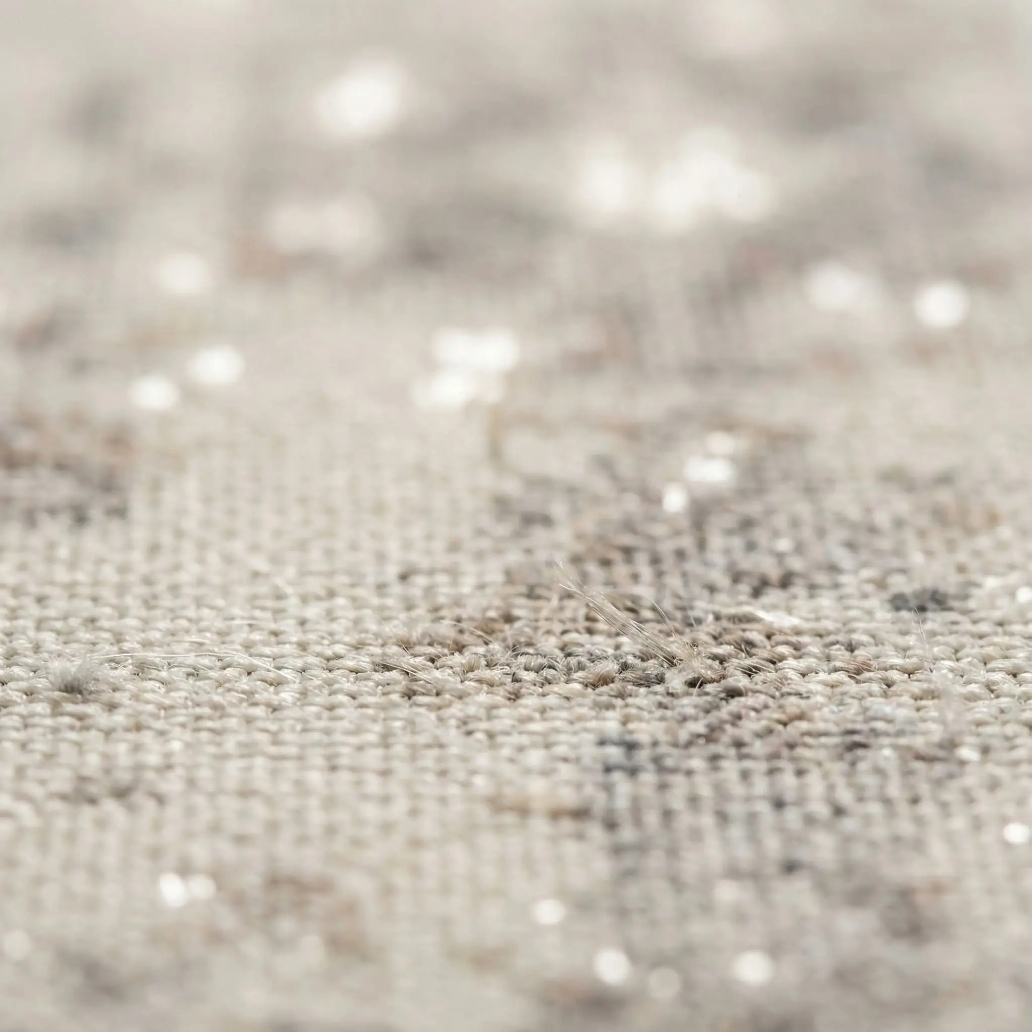 Close-up of a tight, flat power-loomed rug featuring an intentionally faded, distressed printed pattern in cream, taupe, and gray.