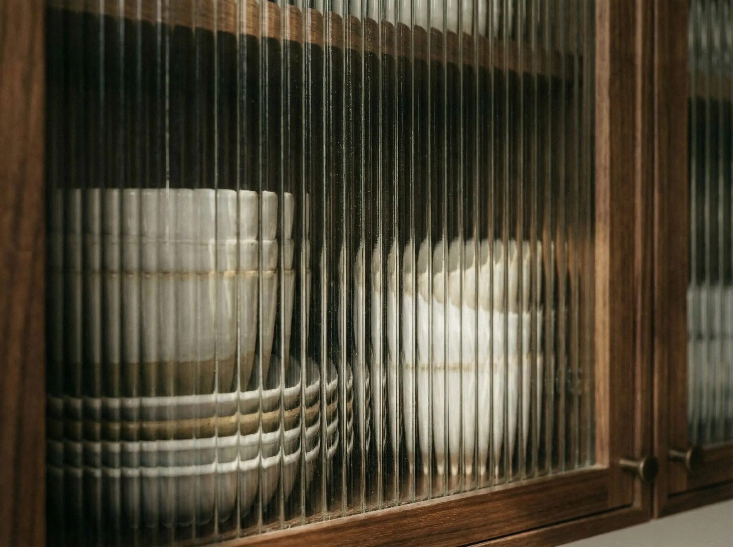 A macro shot highlights the tactile vertical ridges of a reeded glass cabinet door set in a sleek modern frame.