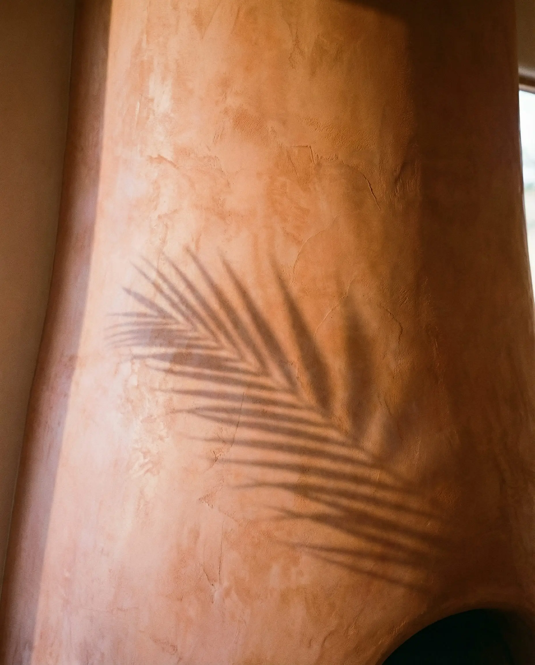 Close-up of a curved fireplace chimney finished in Terracotta Roman Clay plaster, showing the cloudy, matte texture.