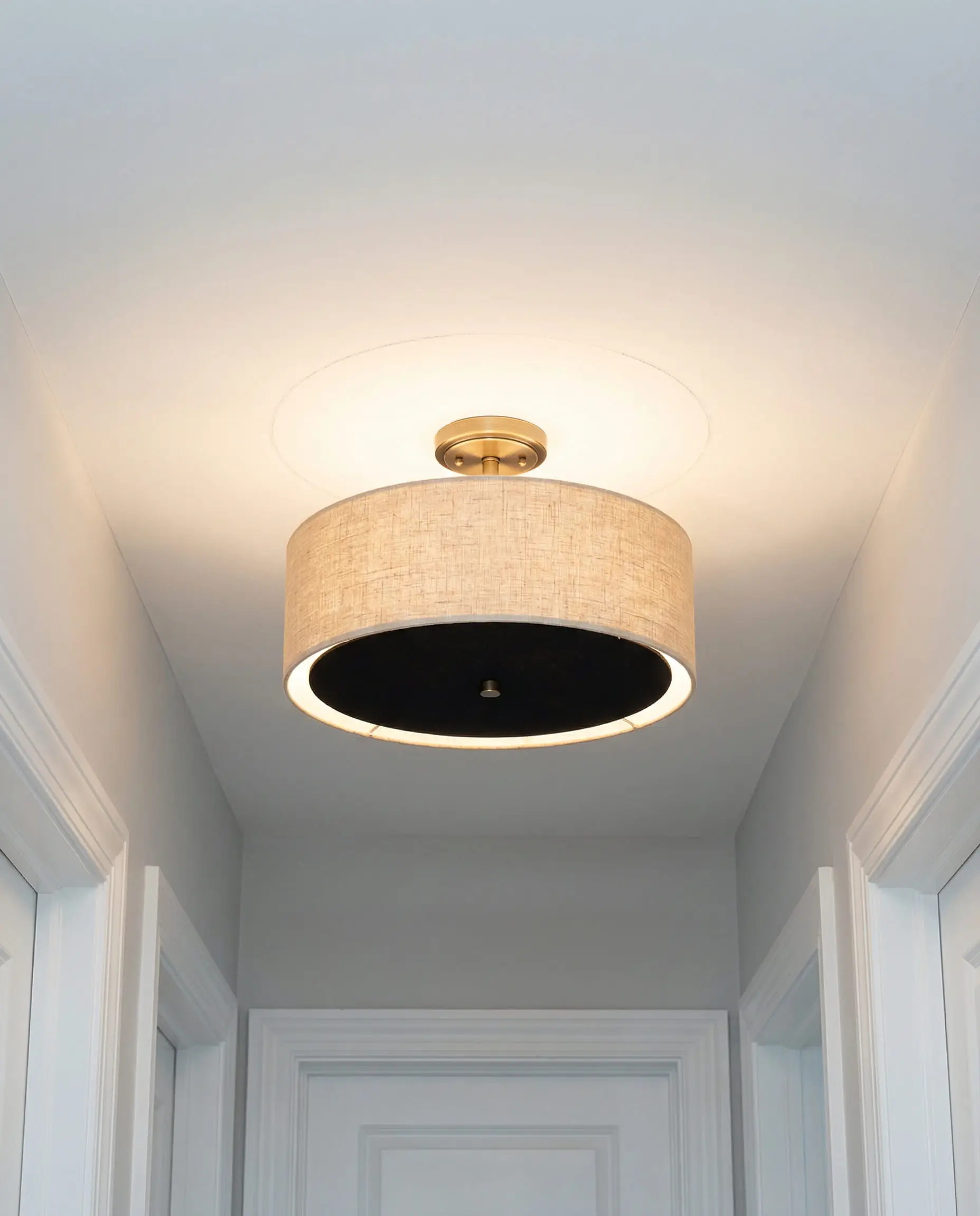 Hallway ceiling showing a linen drum shade semi-flush mount light fixture.