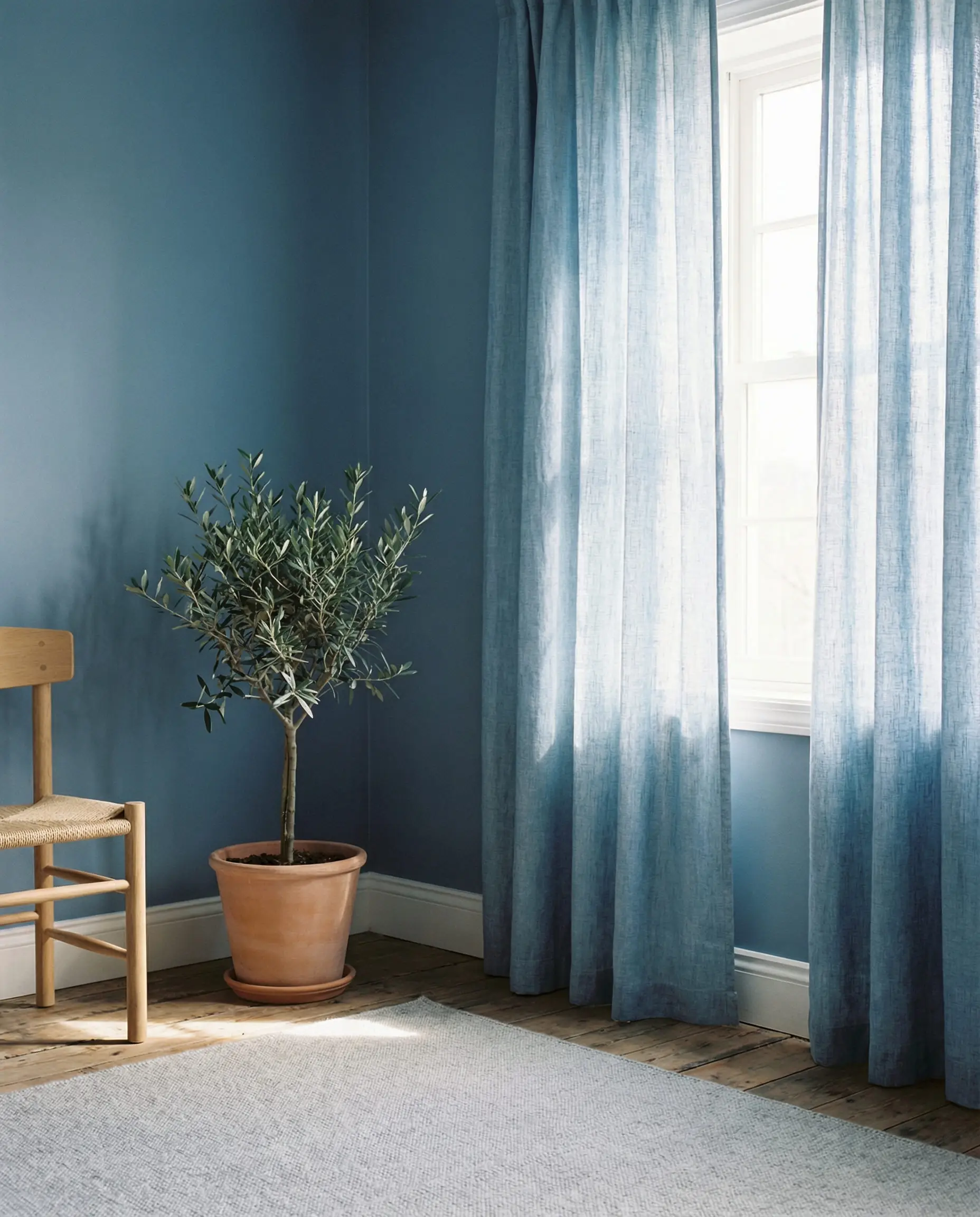 Slate blue wall with lighter chambray blue cotton curtains creating a gradient effect.