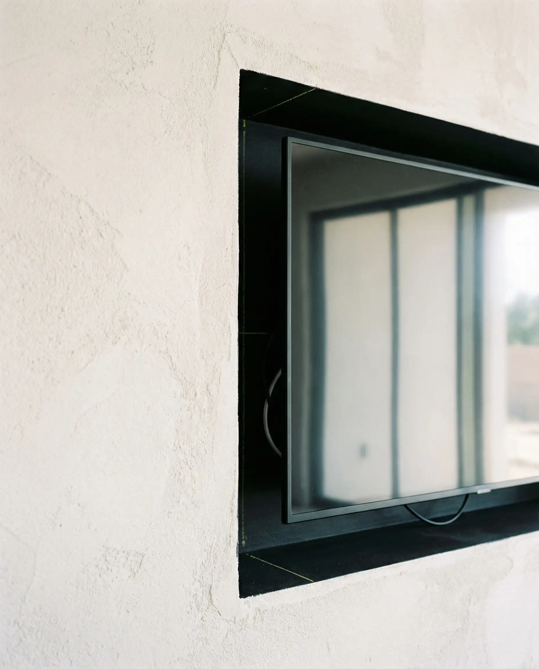 Detail shot of a recessed TV niche showing a shadow gap around the screen for ventilation and future upgrades.