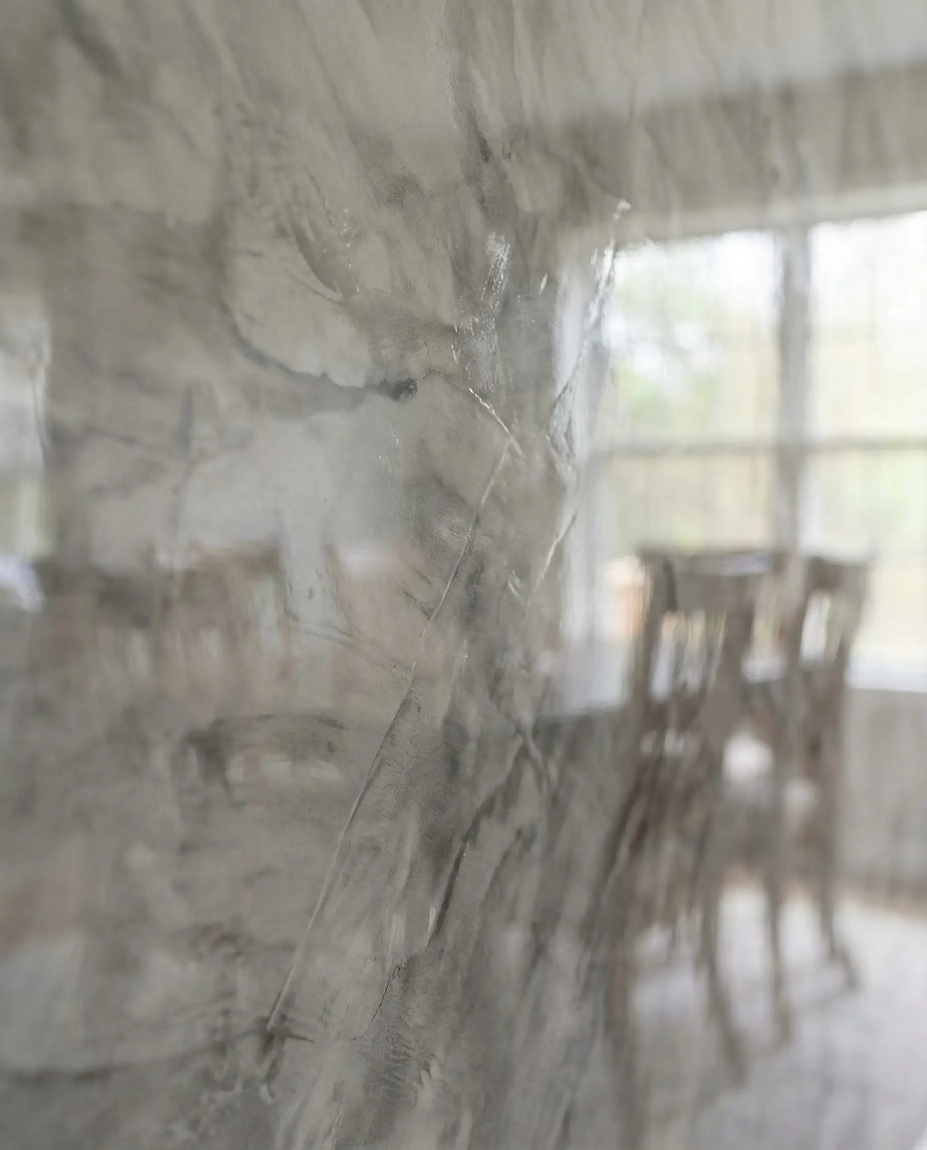 Macro abstract shot of polished Venetian plaster showing marble-like depth, trowel layers, and light reflection.