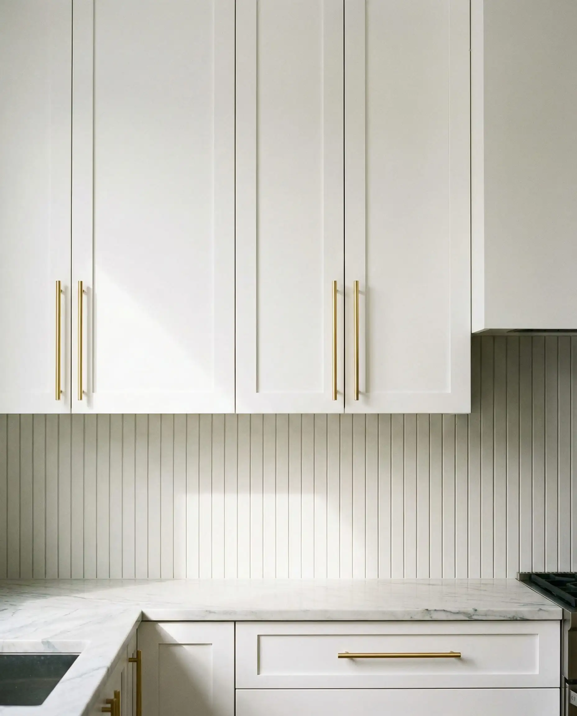 Modern white upper cabinets featuring vertical gold bar pulls instead of knobs.