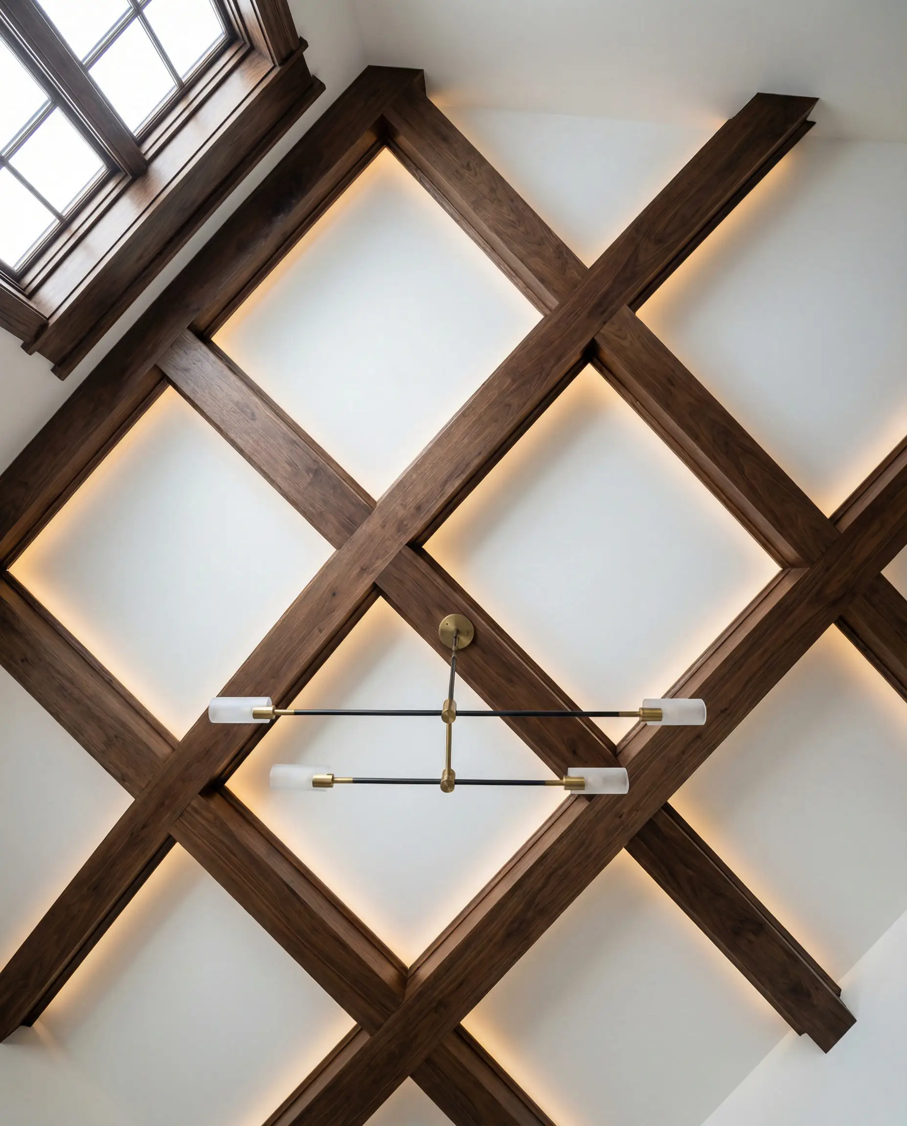 Low angle view of a grid coffered ceiling with matte walnut box beams against white drywall.