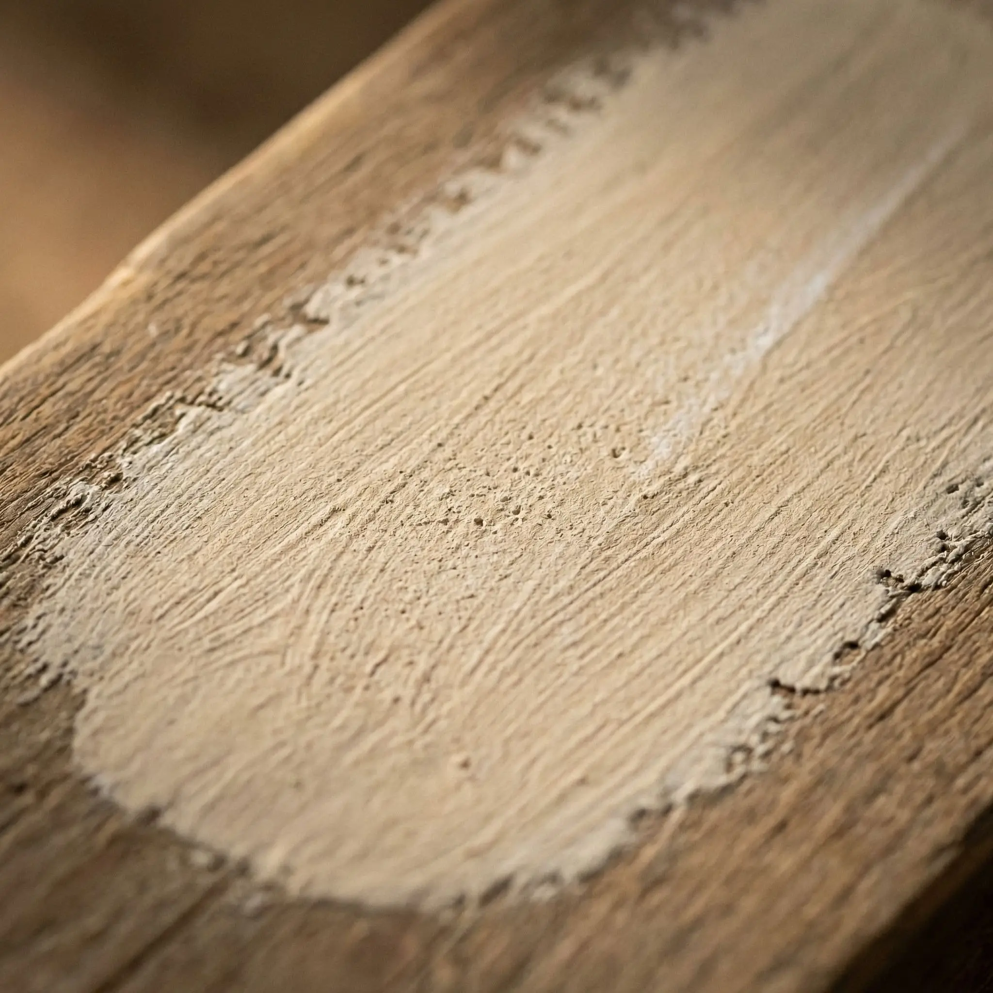 A macro close-up of the best limewash paint colors in warm beige reveals a chalky, porous textured wall paint finish with organic brushstrokes.