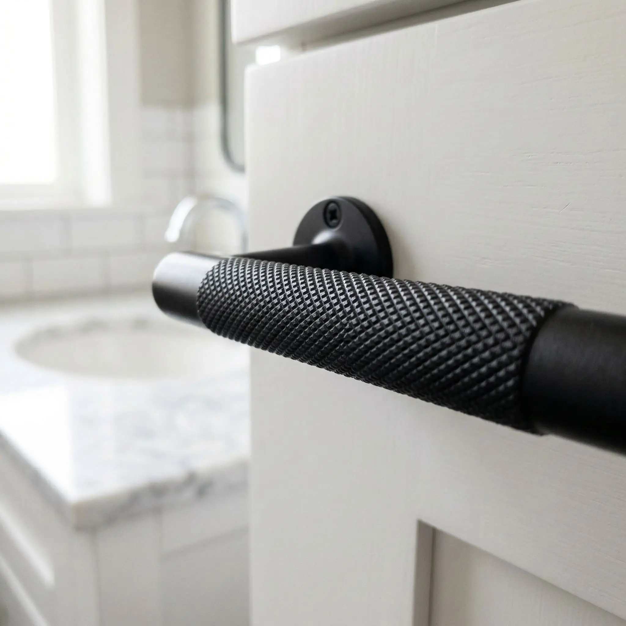 Macro view of heavy knurled matte black metal bar pulls installed on a freshly painted bathroom vanity cabinet.