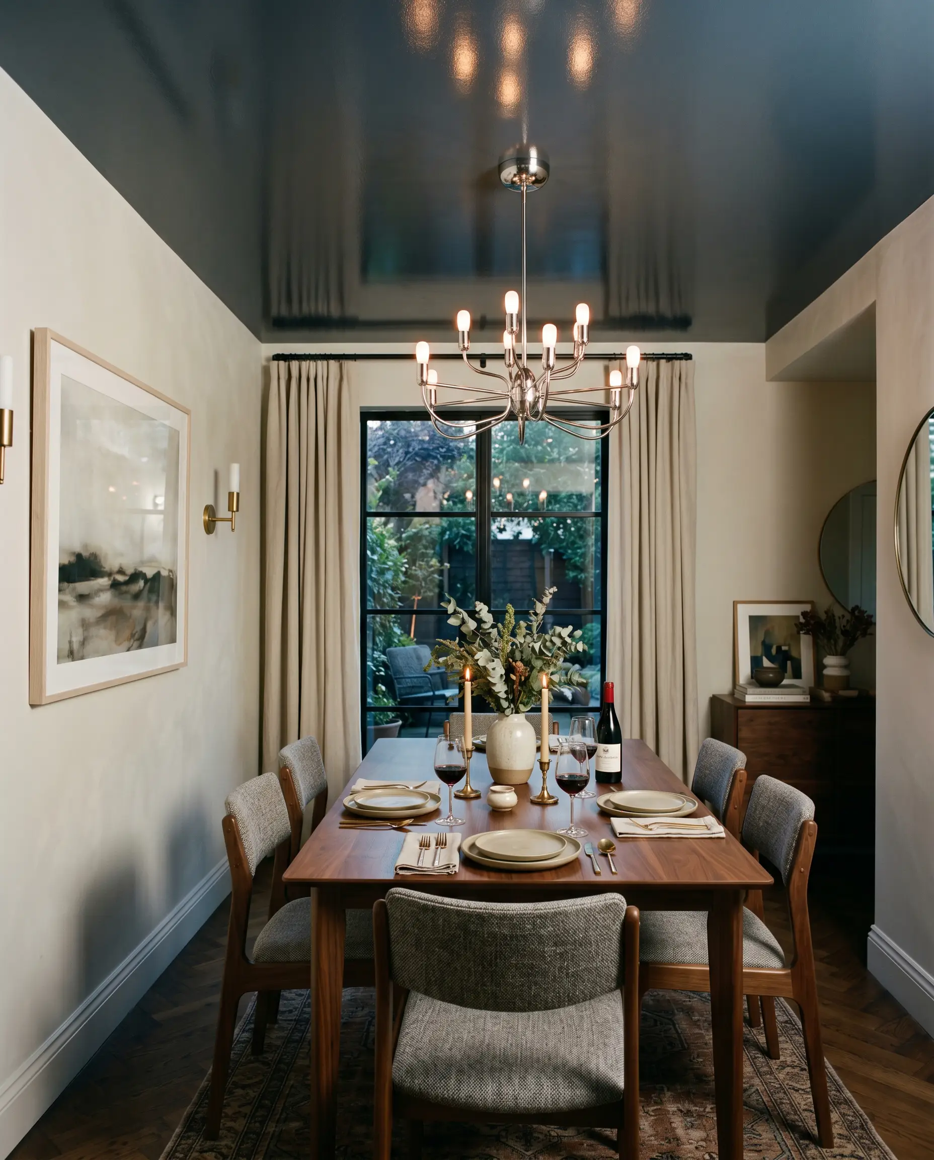 A polished chrome chandelier hangs below an intimate dining room ceiling painted in a high-gloss finish of Sherwin-Williams Sea Mariner (Hex #434A54).