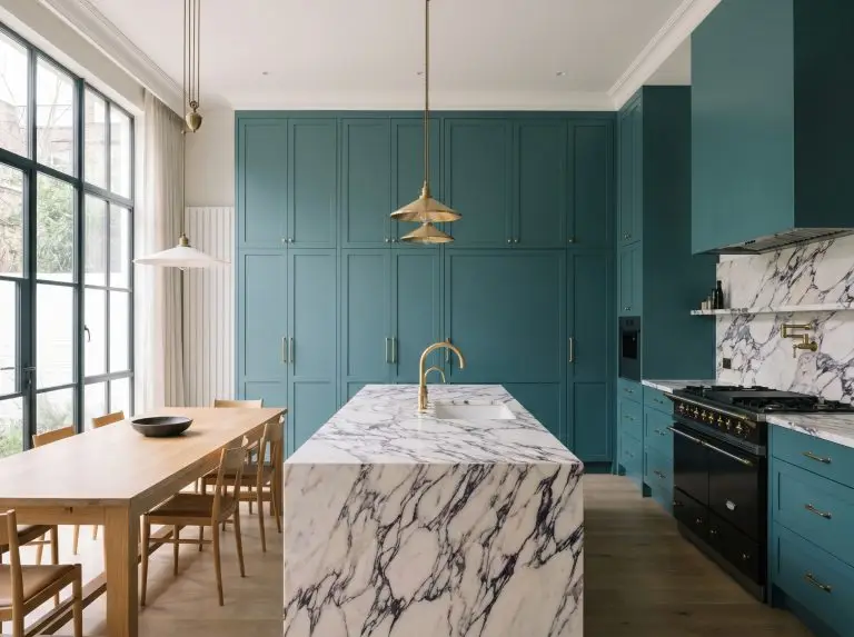 Heavy, integrated kitchen cabinetry painted in a rich teal pairs elegantly with Calacatta Viola marble countertops and unlacquered brass hardware.