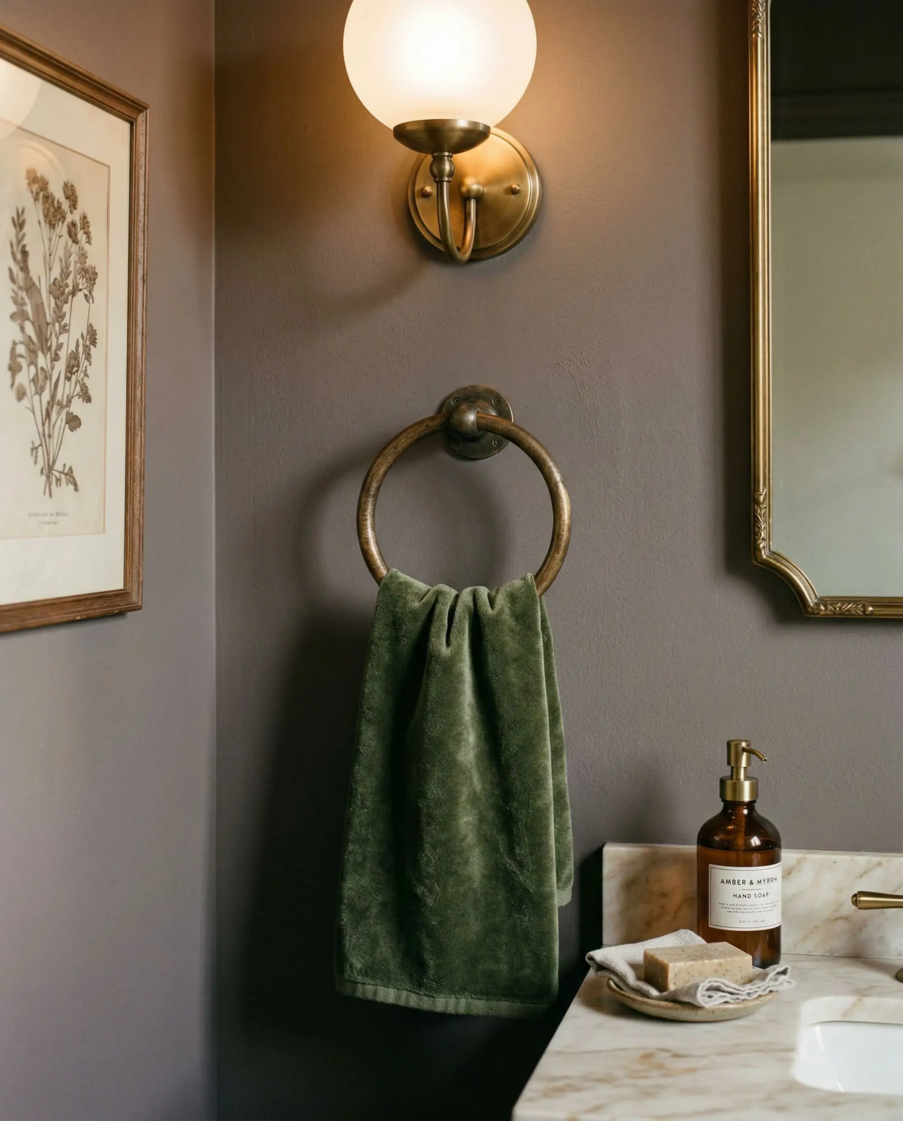An unlacquered brass towel ring holds a rich velvet hand towel against a wall painted in Behr Curtain Call.