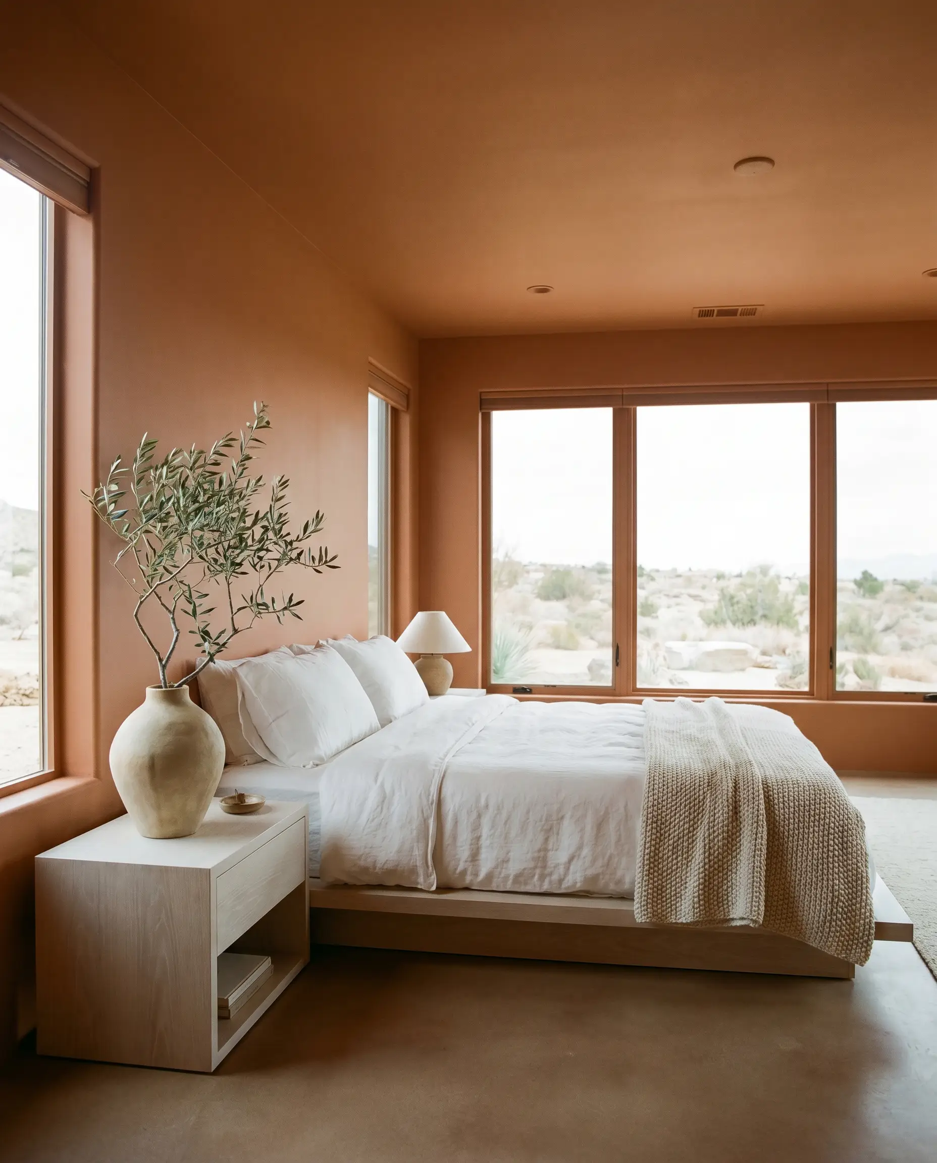 Crisp white linen bedding and a light white oak nightstand stand out against a continuous wash of Benjamin Moore Southwest Pottery (Hex #975F57).