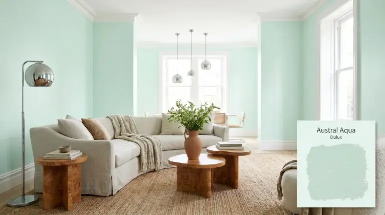 A curved slipcovered sofa and warm burl wood accent tables anchor a Scandi-modern living room painted in Dulux Austral Aqua (Hex #e2f6ef).