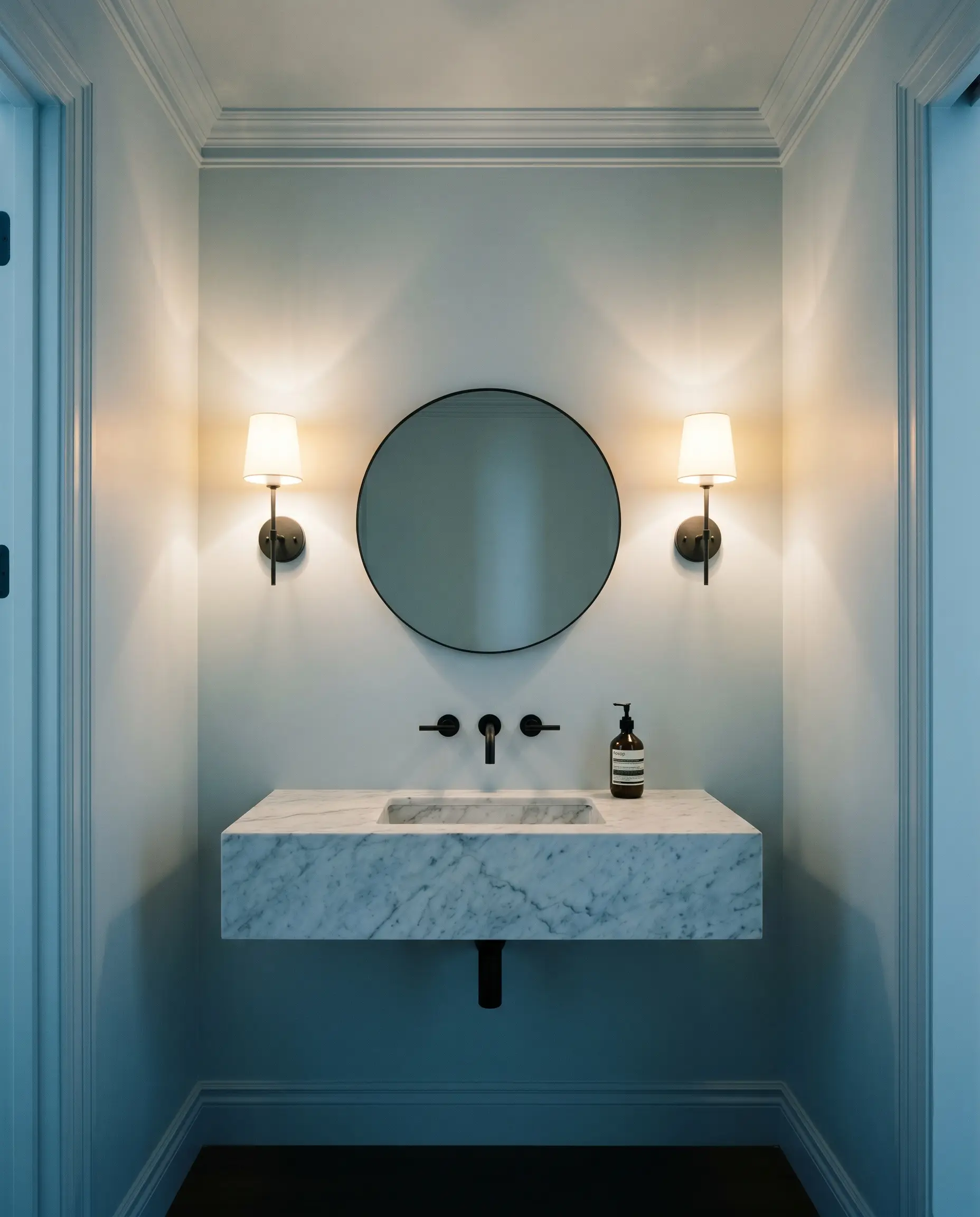 A windowless powder room is completely color-drenched in Dulux Mineral Mist (Hex #C3D8E3), featuring a floating marble sink and matte black iron fixtures.